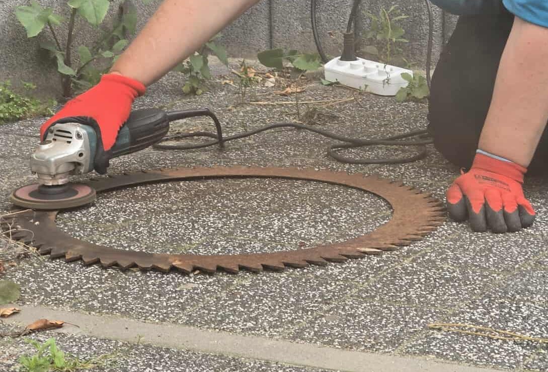 Artysta w trakcie pracy – szlifowanie metalowego koła zębatego na warsztatach.