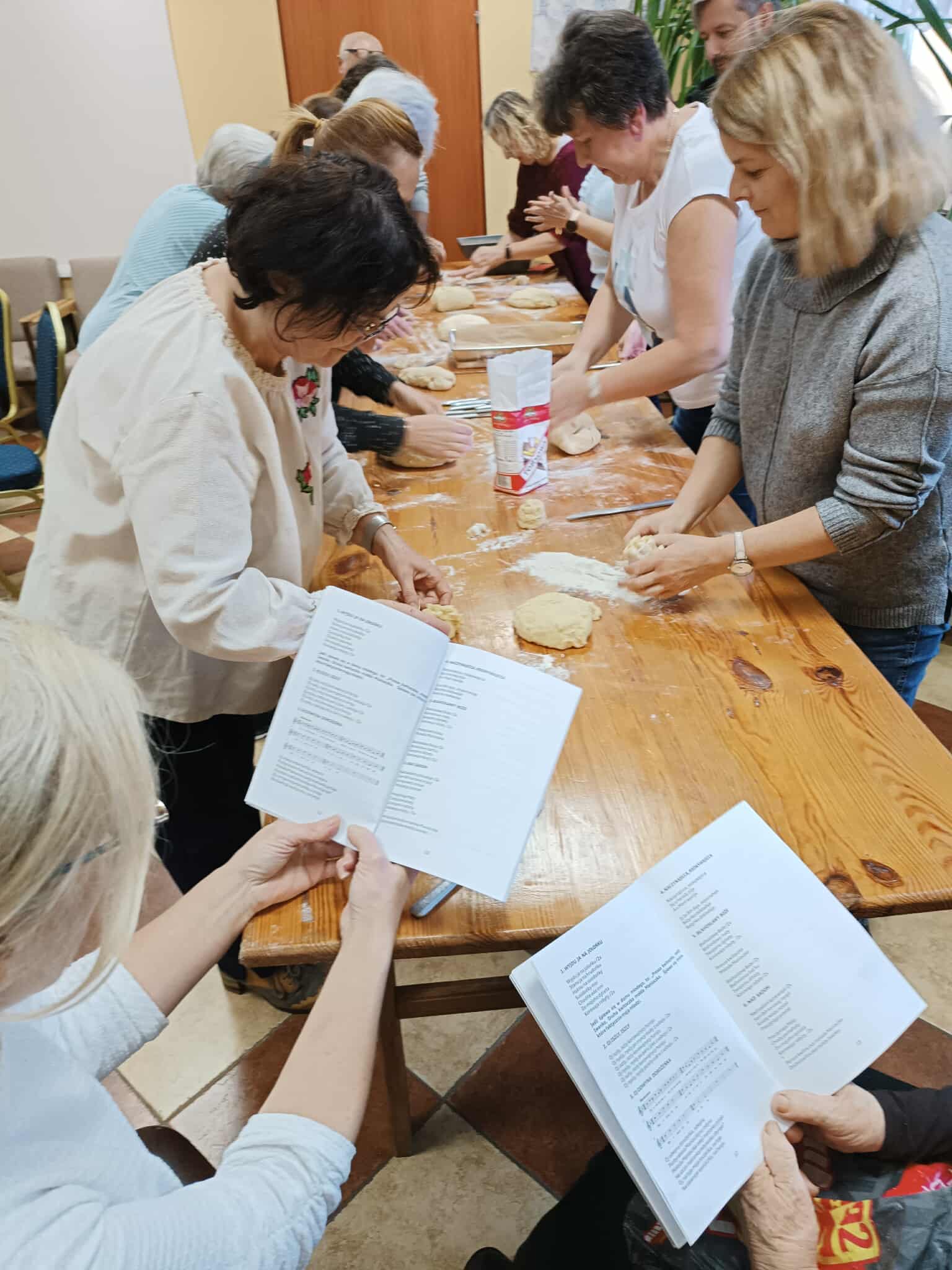 zdjęcie grupy osób przy stole, na pierwszym planie otwarte książki