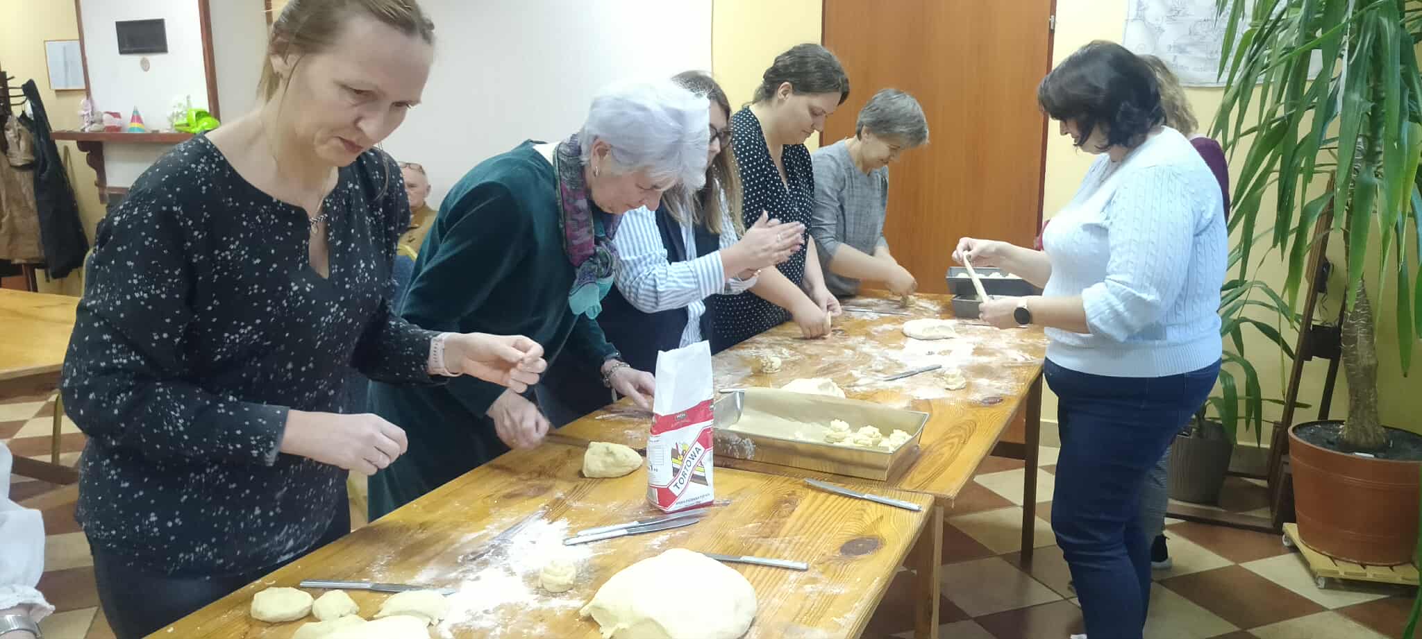 zdjęcie grupy kobiet przy stole, lepiących ciasto