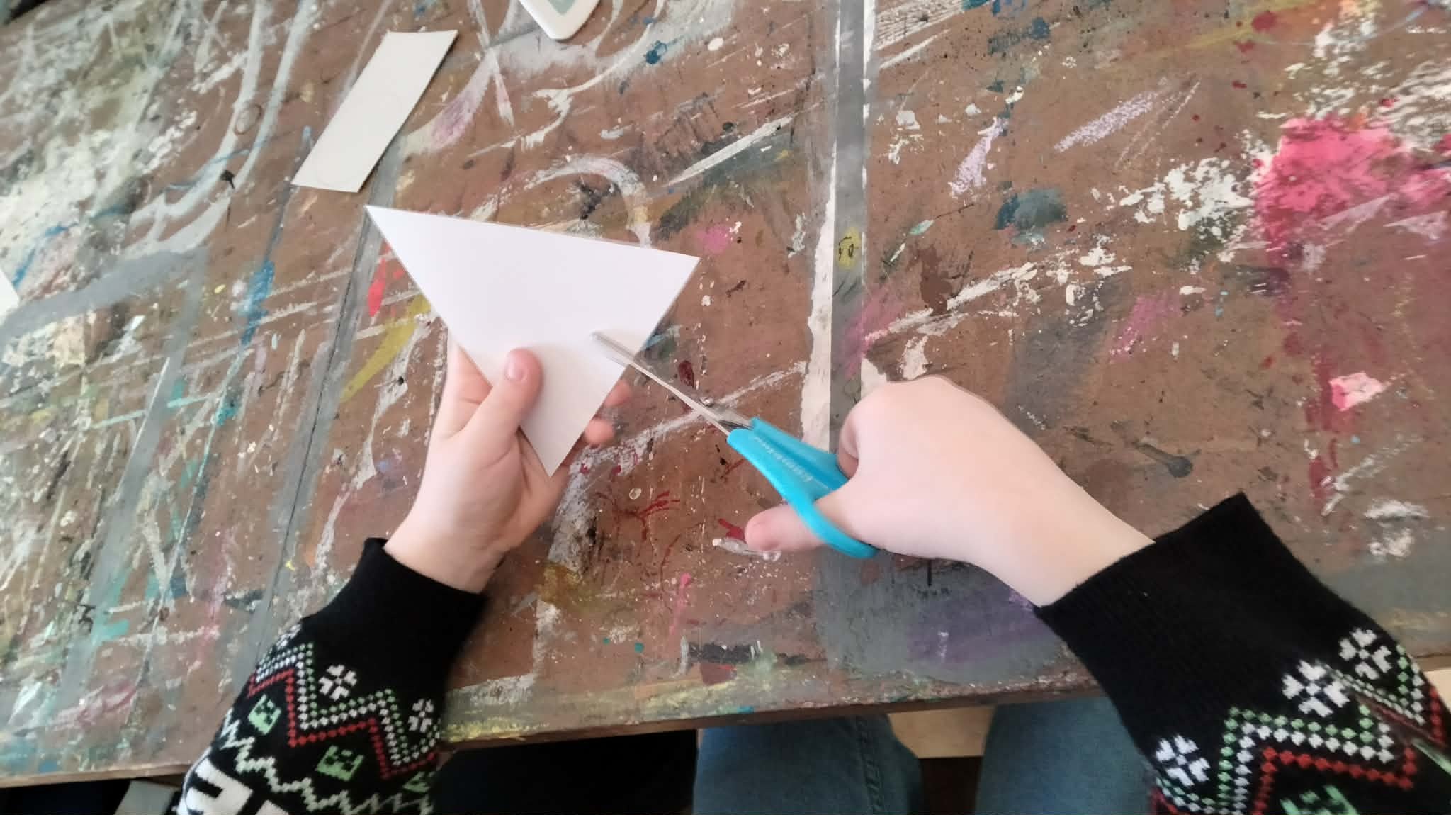 Dzieci siedzą przy stole i pracują nad stworzeniem leśnych zwierząt.