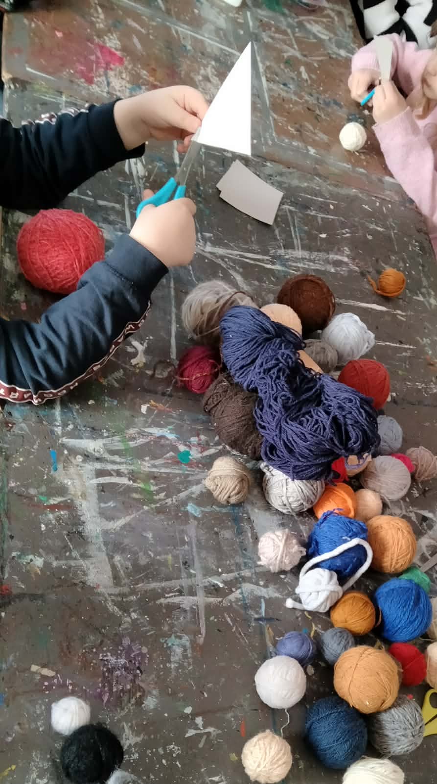 Dzieci siedzą przy stole i pracują nad stworzeniem leśnych zwierząt.