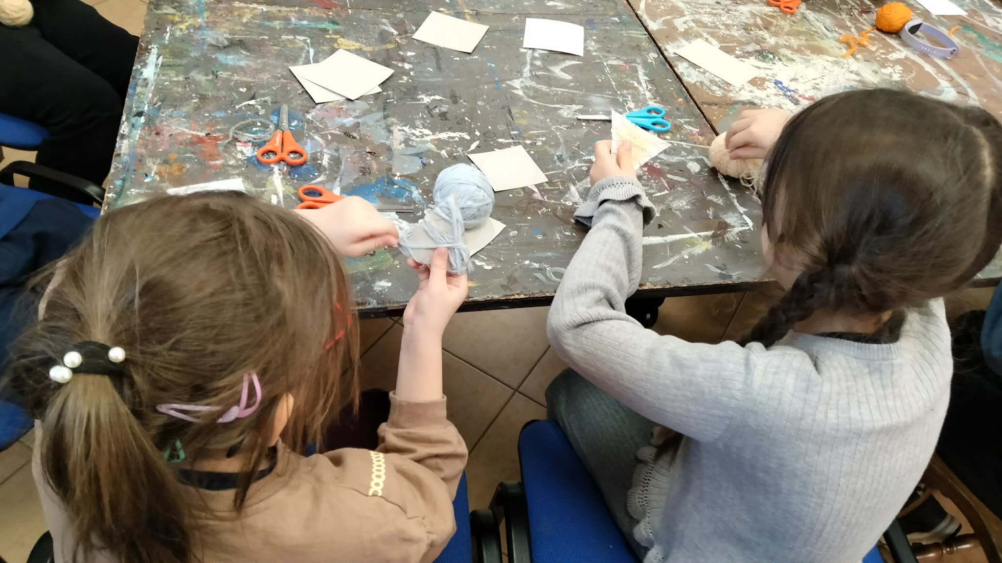 Dzieci siedzą przy stole i pracują nad stworzeniem leśnych zwierząt.