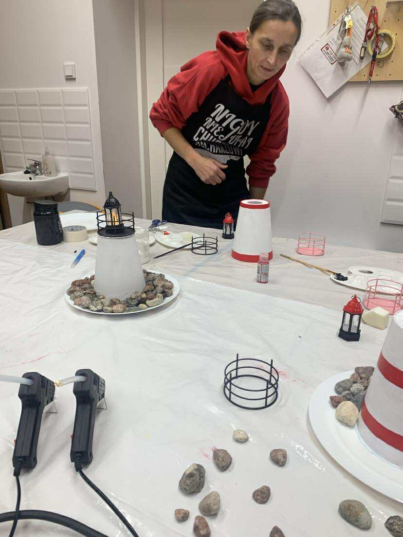 Zdjęcie kobiety stojącej przy stole zastawionym materiałami niezbędnymi na warsztaty.