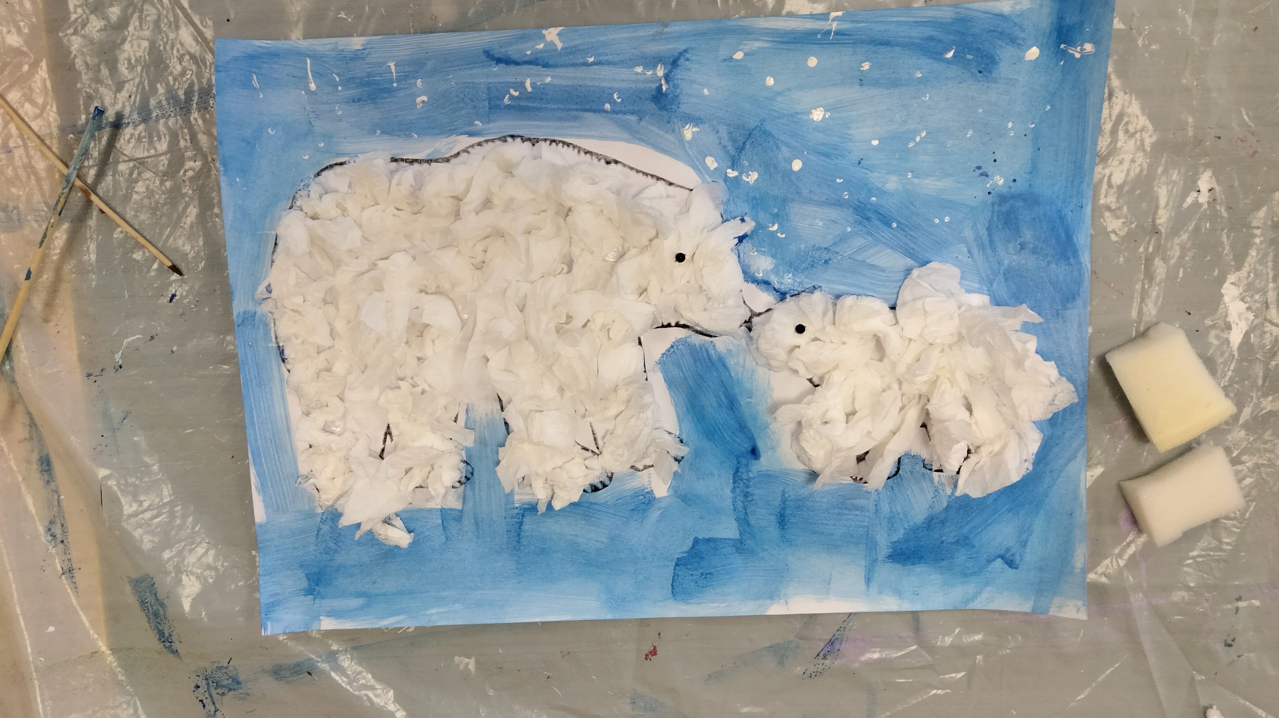 Zdjęcie przedstawia pracę plastyczną - dwa niedźwiedzie polarne na niebieskim tle.