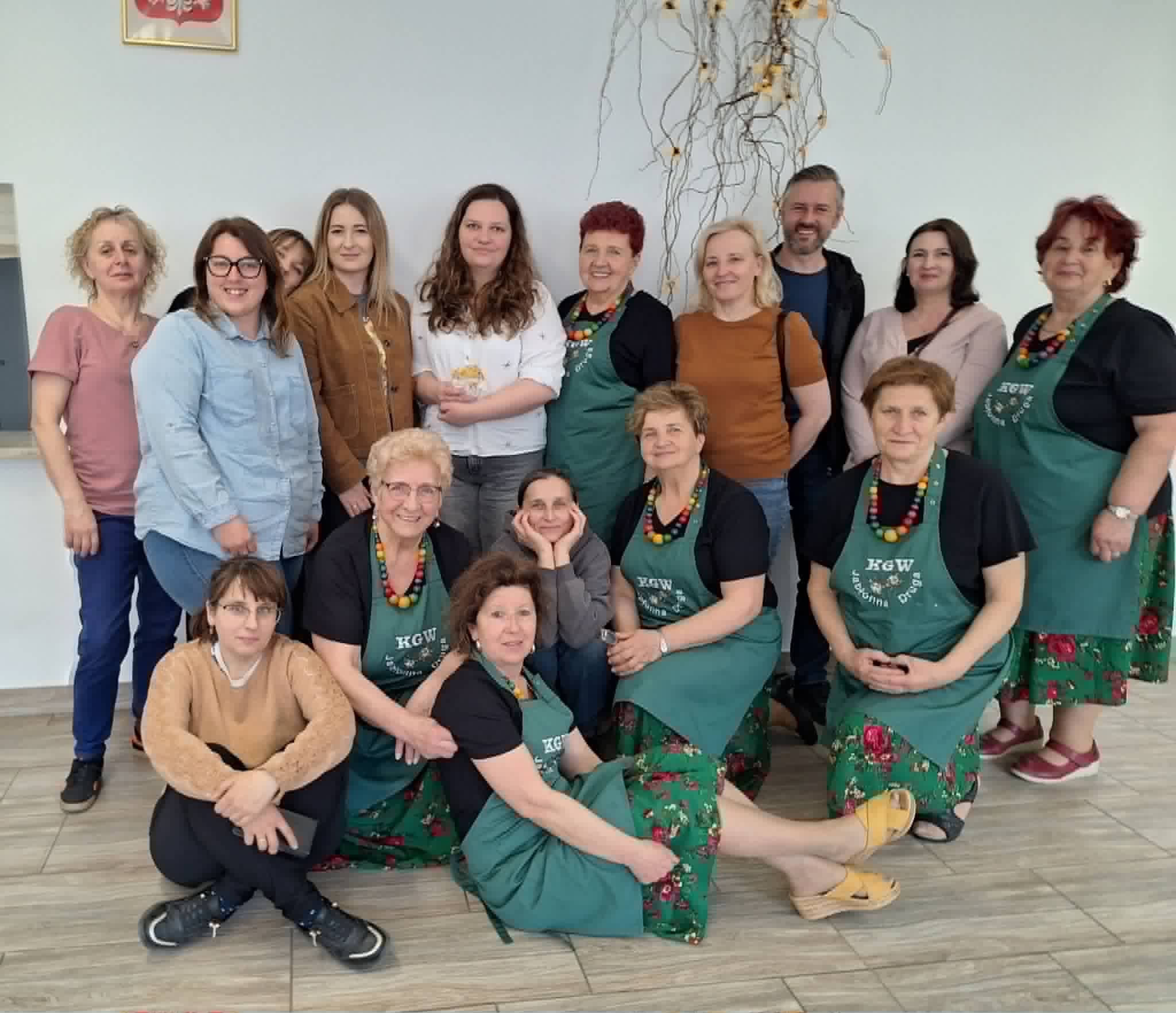 Grupa osób - połowa z nich ma na sobie takie same zielone fartuchy.