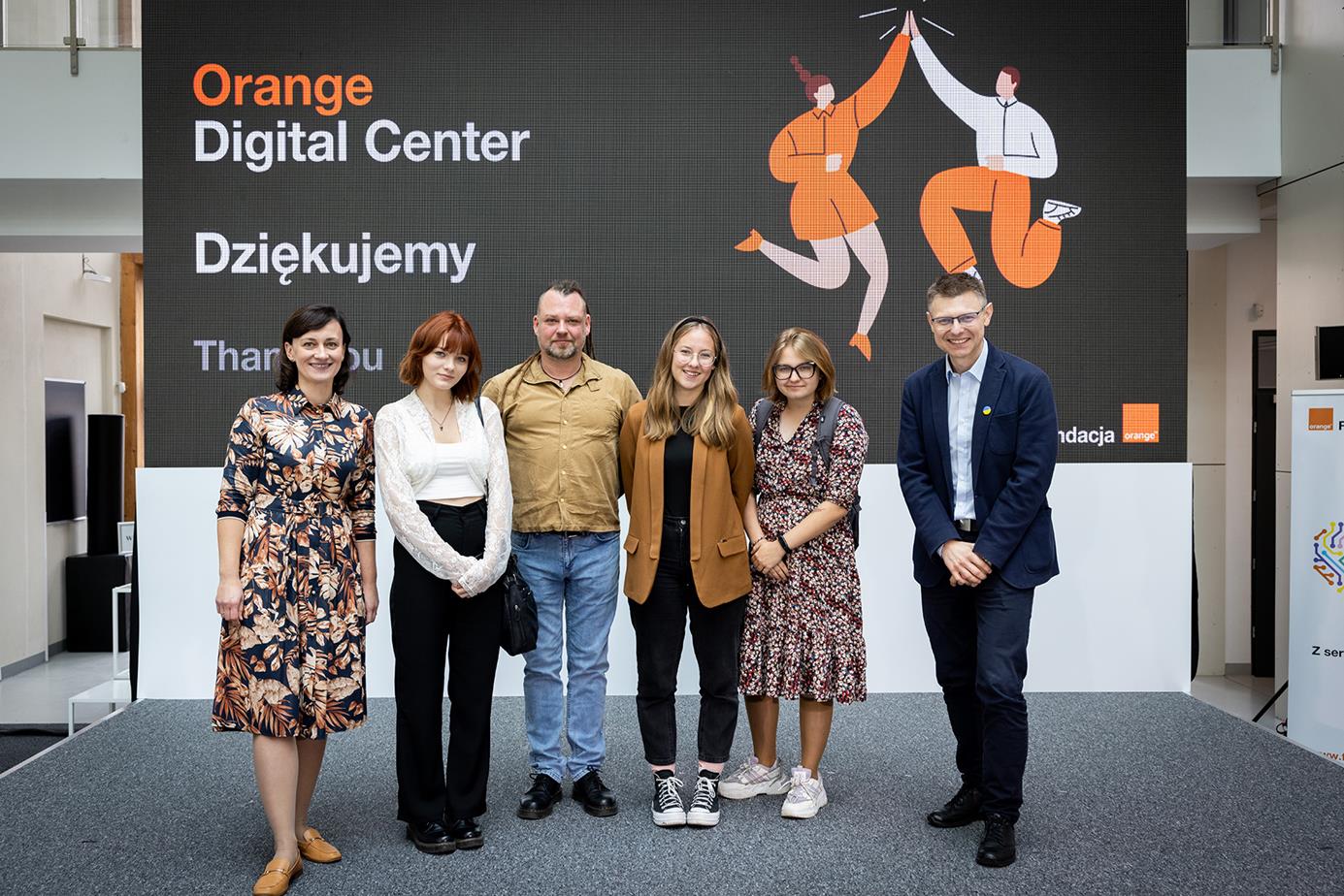 Na zdjęciu szóstka szczęśliwych ludzi. Delegacja z Pracowni Orange w Gubinie stoi z oficjelami Fundacji Orange. W tle baner Orange Digital Center.