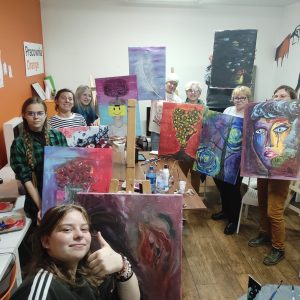 Na zdjęciu uczestniczki projektu "Malowanie emocjami" z dumą pokazują swoje namalowane dzieła. Prace są niesamowite a po osobach na zdjęciu widać, że warsztaty były energetyczne i przyniosły wiele radości.