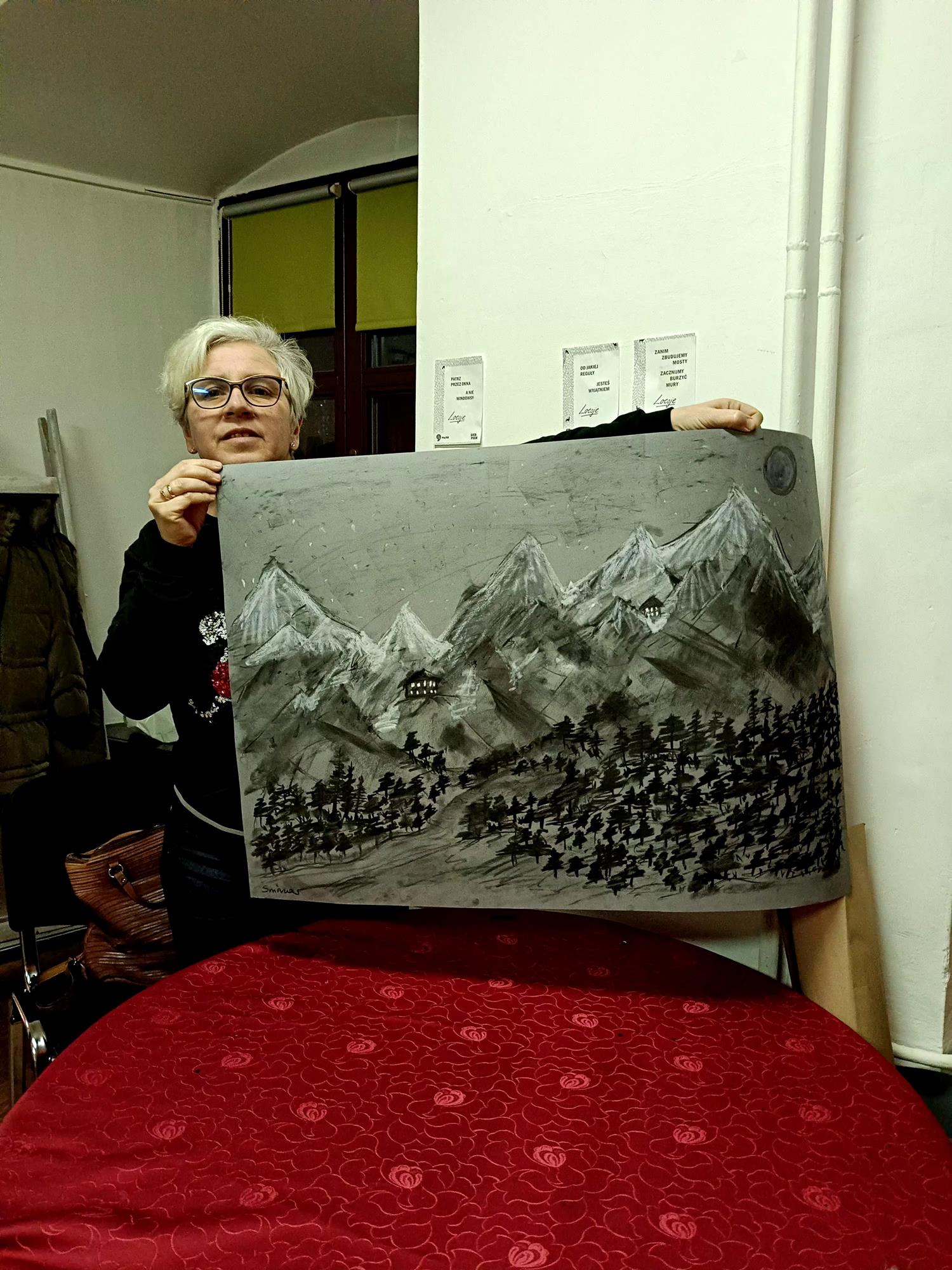 kobieta trzyma obraz namalowany węglem