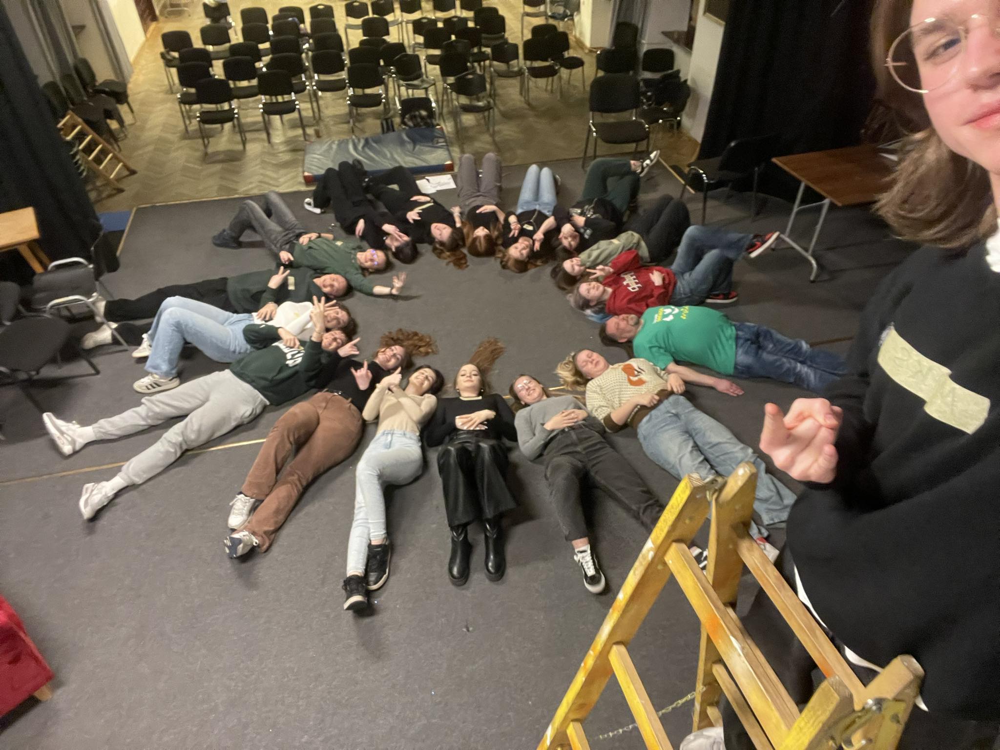 Na zdjęciu widać dwudziestkę młodych ludzi leżących na podłodze. Wszyscy razem tworzą coś co przypomina słoneczko. Bo też cała grupa projektowa jest bardzo pogodna.