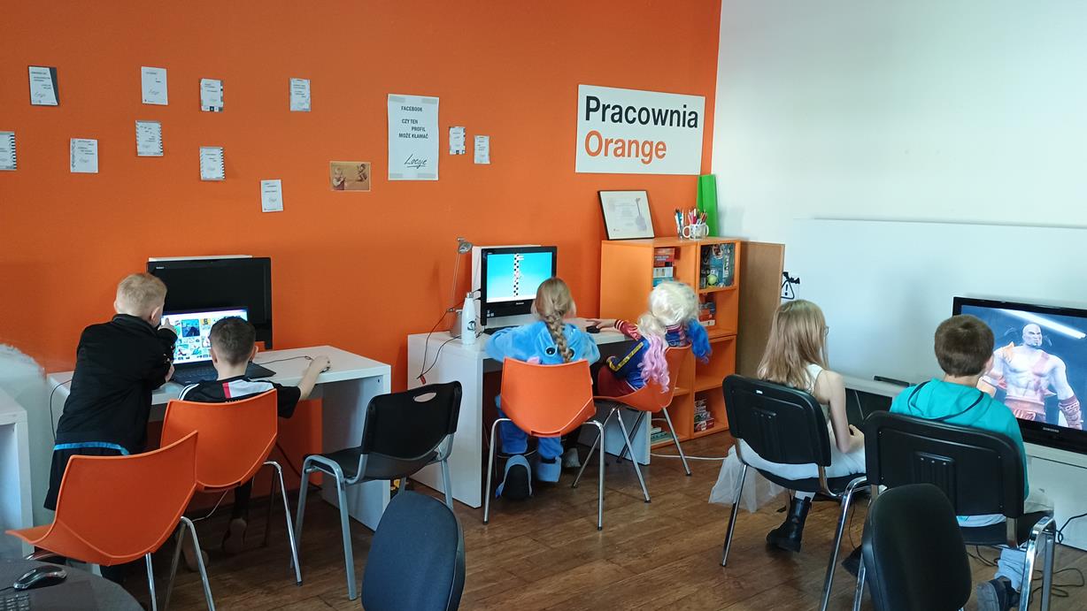 na zdjęciu widzimy szóstkę dzieci w pracowni orange grają na komputerach