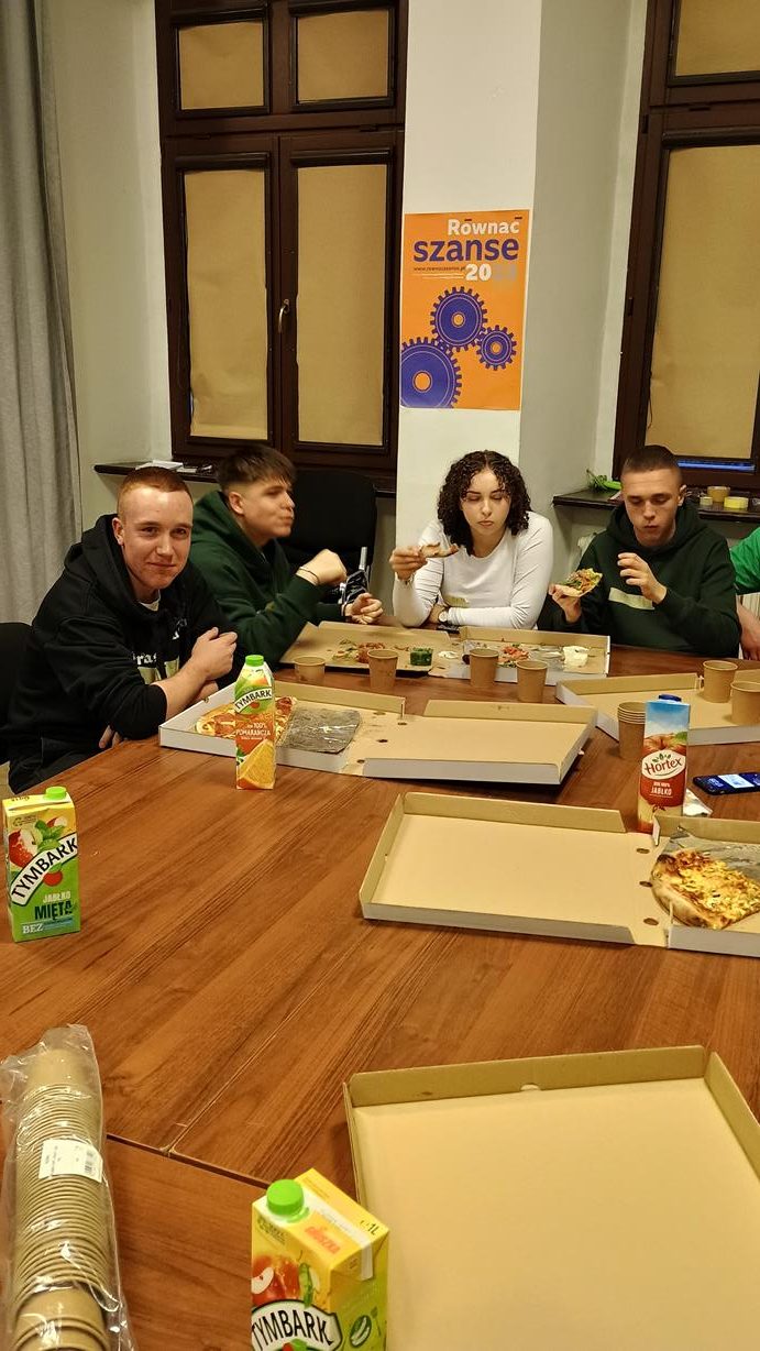 zdjęcie młodych osób przy stole jedzą pizze