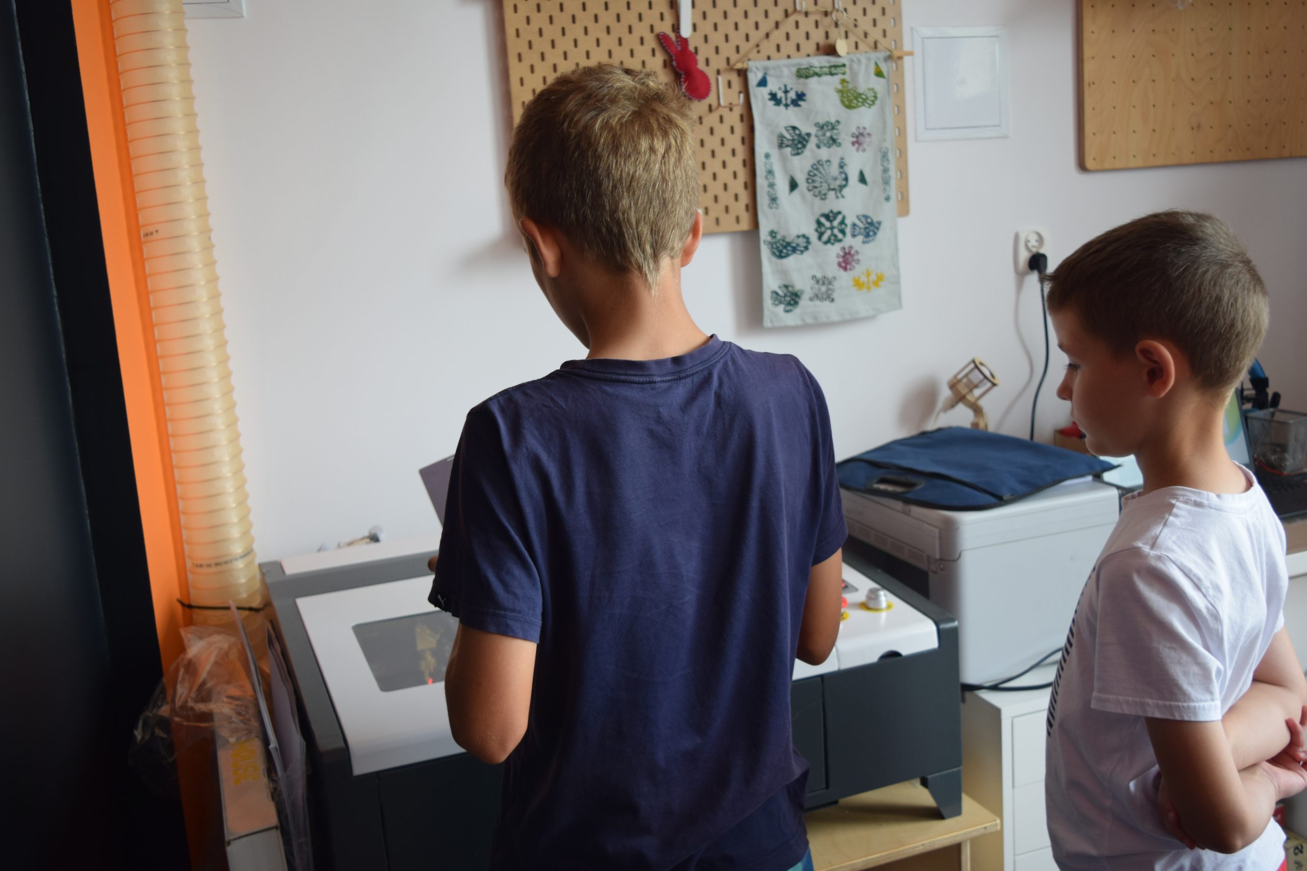 Dwóch chłopców stojących przy drukarce.