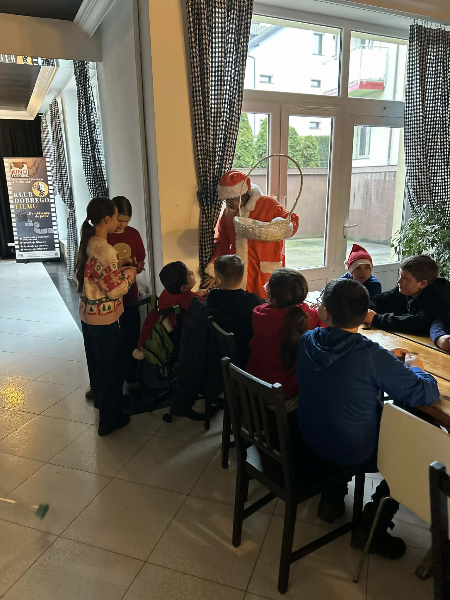 Kobieta w stroju św. Mikołaja rozdaje dzieciom prezenty.