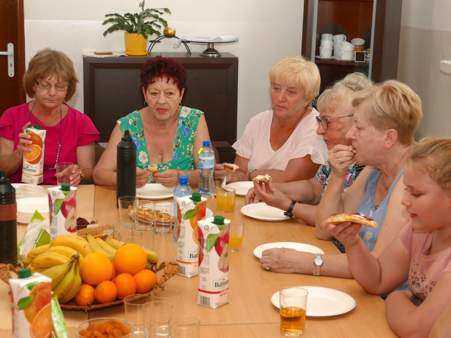 grupa starszych kobiet siedzą razem przy stole i jedzą wspólnie posiłek