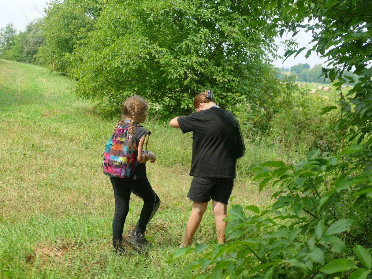 Grupa osób idących drogą polną.