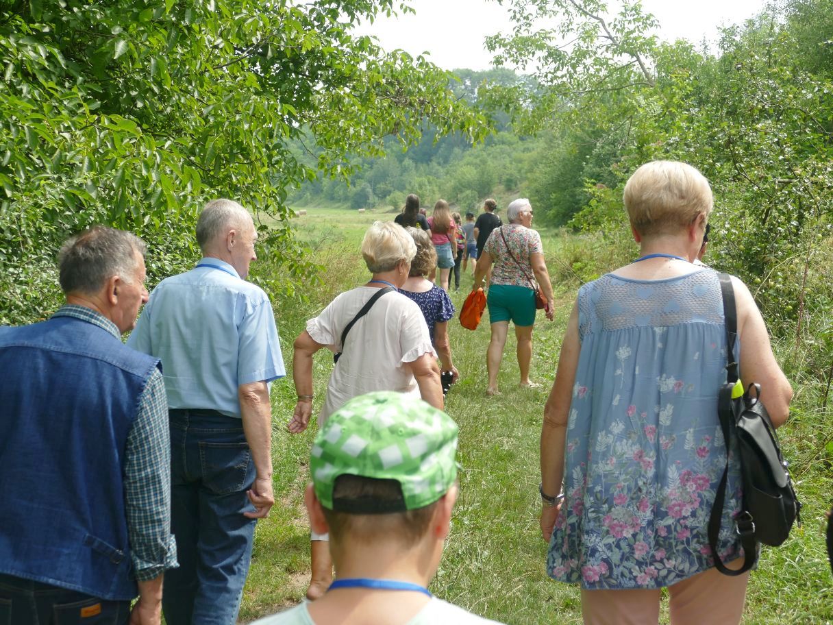 Grupa osób idących drogą polną.