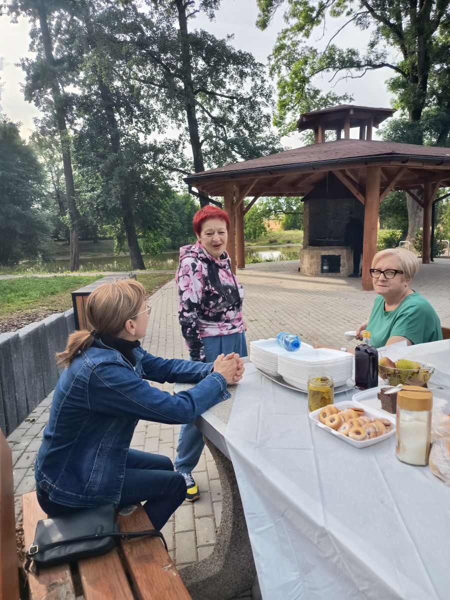 Trzy kobiety przy stole z poczęstunkiem na zewnątrz