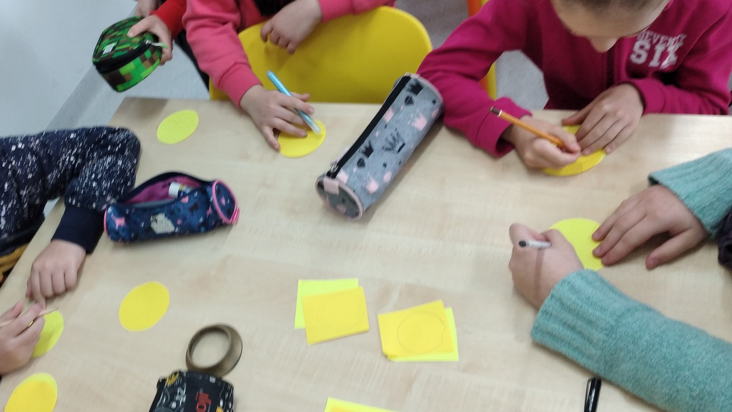 dzieci rysują uśmiechnięte minki na żółtych karteczkach