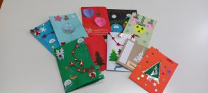Kilka kart Bożonarodzeniowych, wykonanych z kolorowego papieru, ozdobionych różnymi świątecznymi elementami