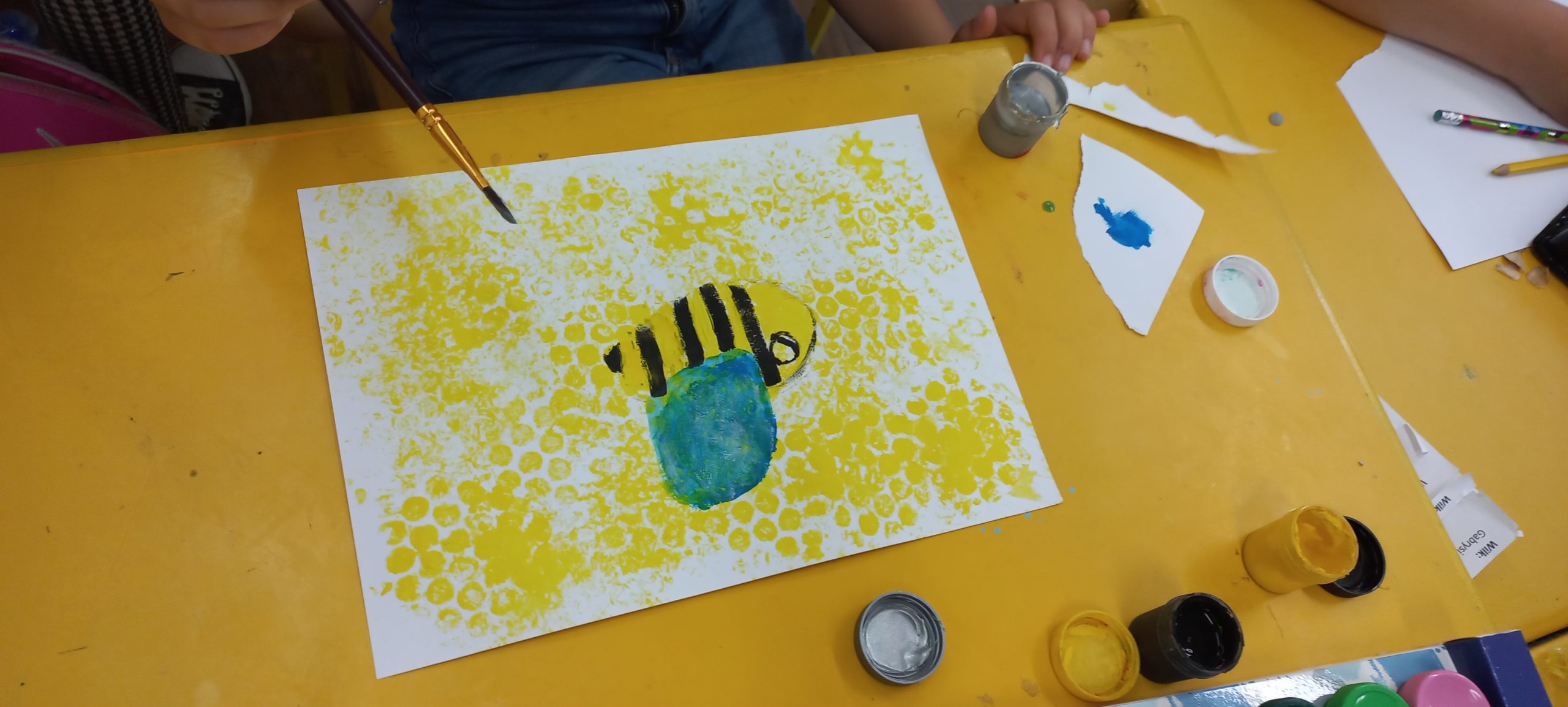 na białej kartce namalowana pszczółka i plastry miodu