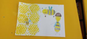 na białej kartce namalowane żółte plastry miodu oraz uśmiechnięte pszczółki