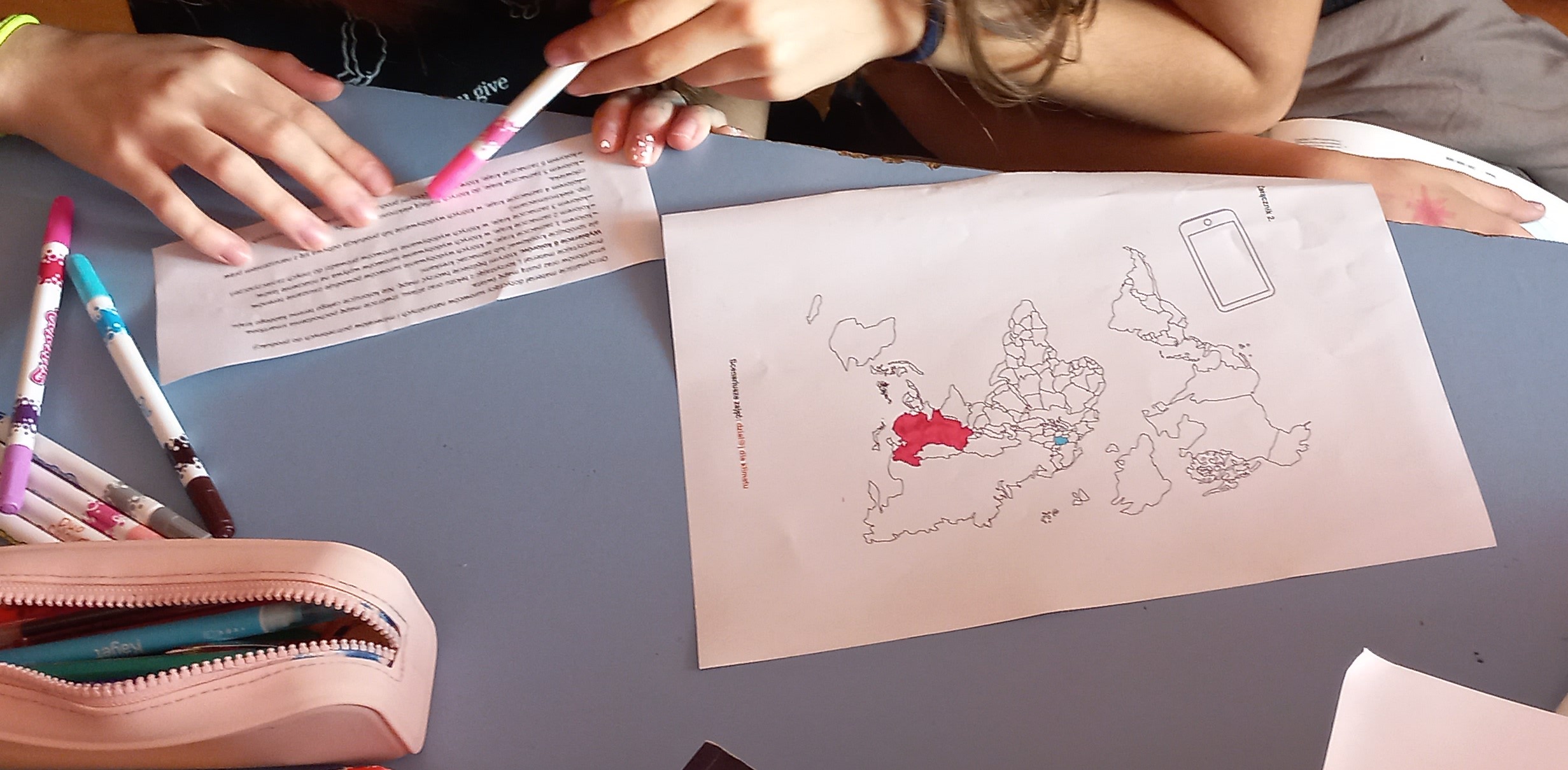 dzieci kolorują mapę świata i zaznaczają coś na niej