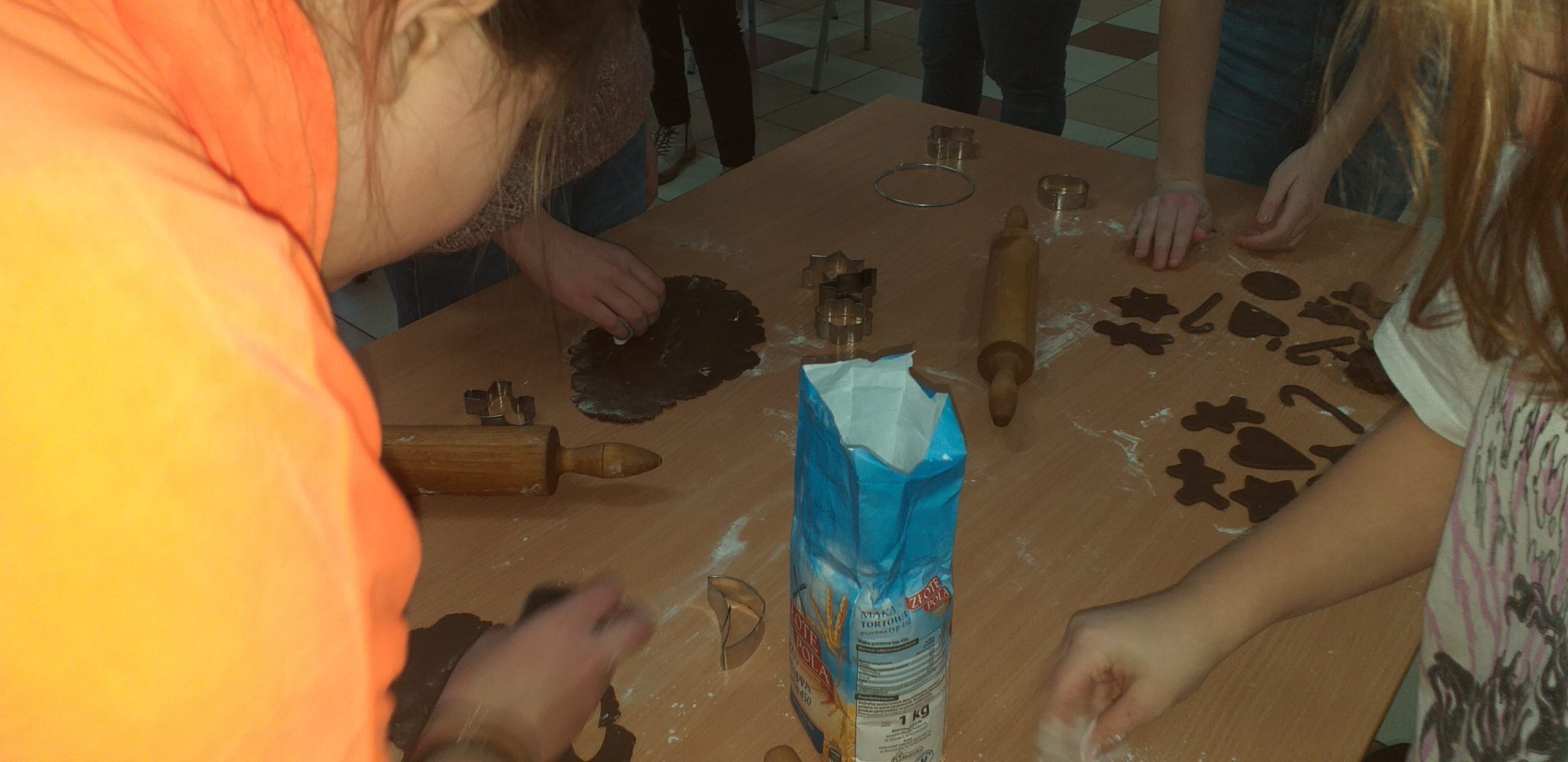 przy stole grupa dzieci wycina foremkami kształty pierników
