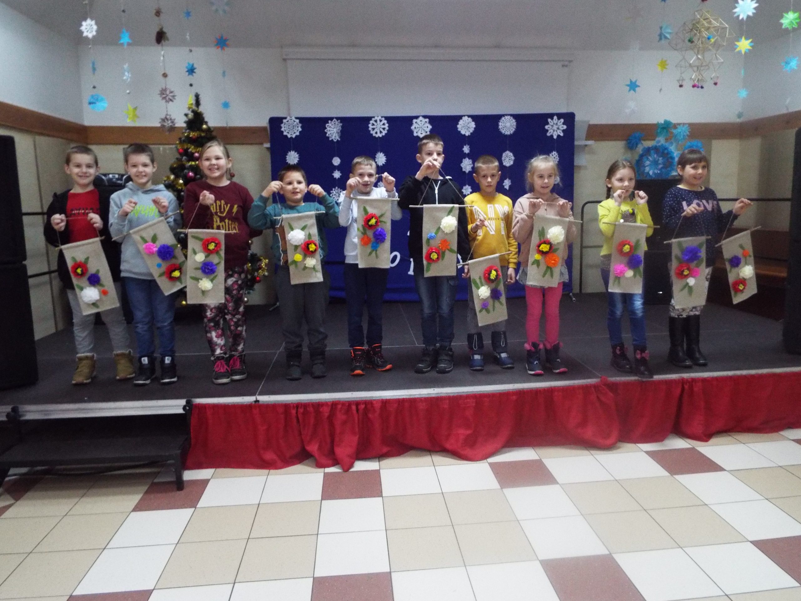 Grupa dzieci prezentuje własnoręcznie zrobione makatki.