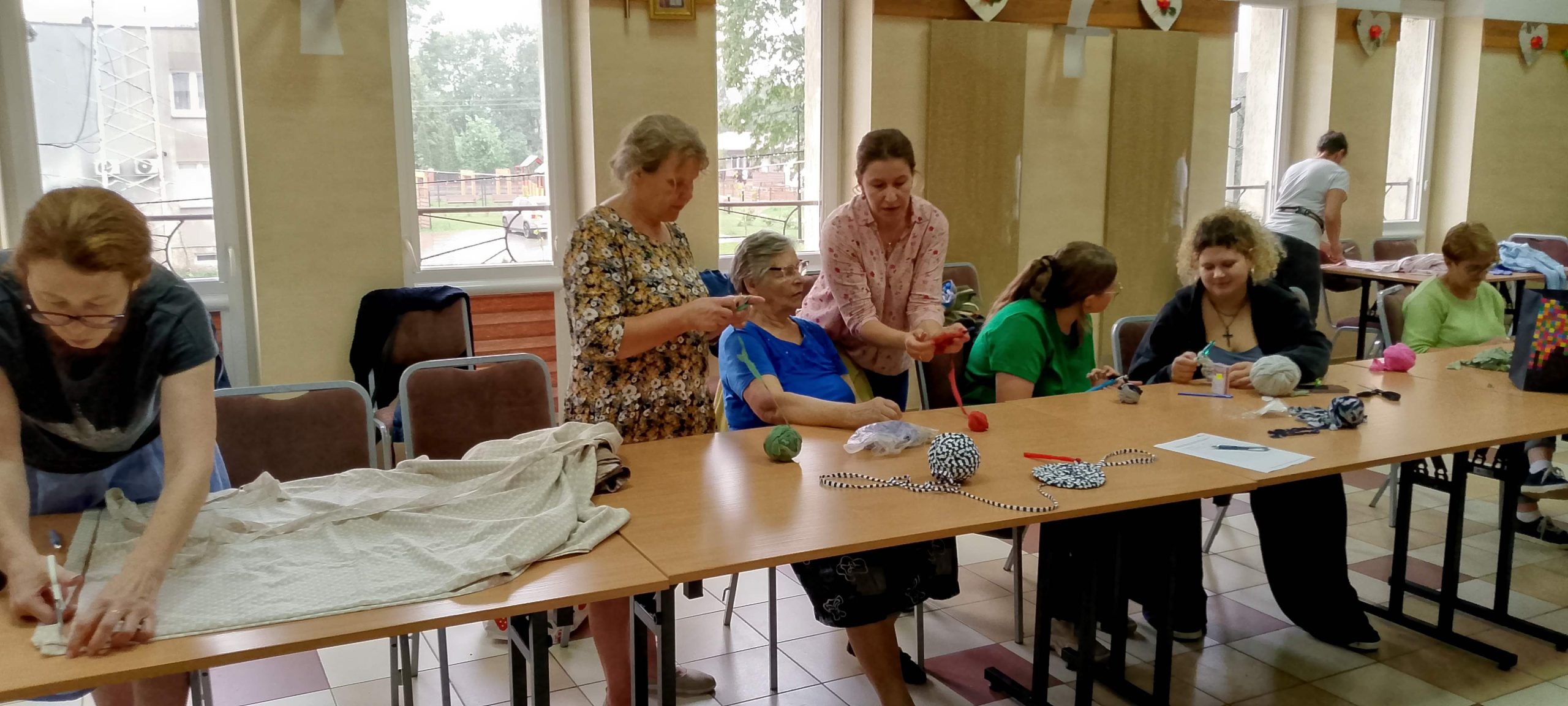 Instruktorka pokazuje technikę szydełkowania.