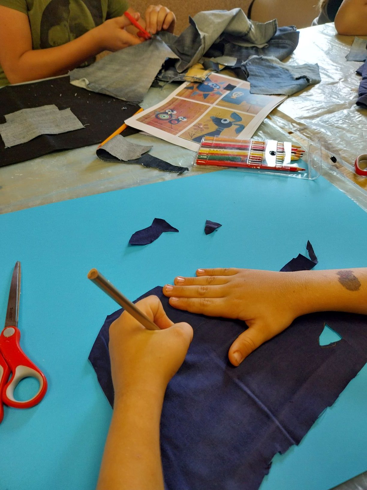 na starych dżinsach uczestnik zajęć rysuje rybki, które potem będzie wycinał