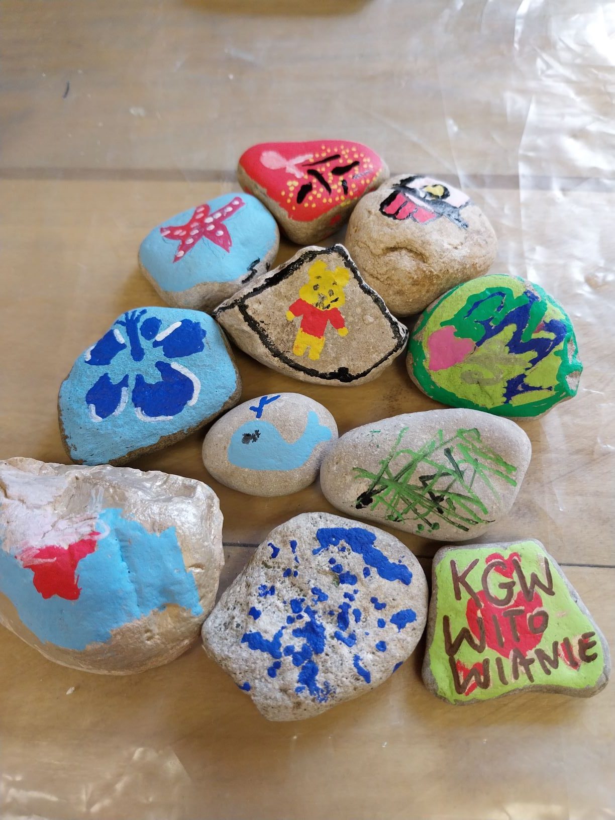na stole leży11 kamyków, wcześniej ozdobionych akrylowymi mazakami