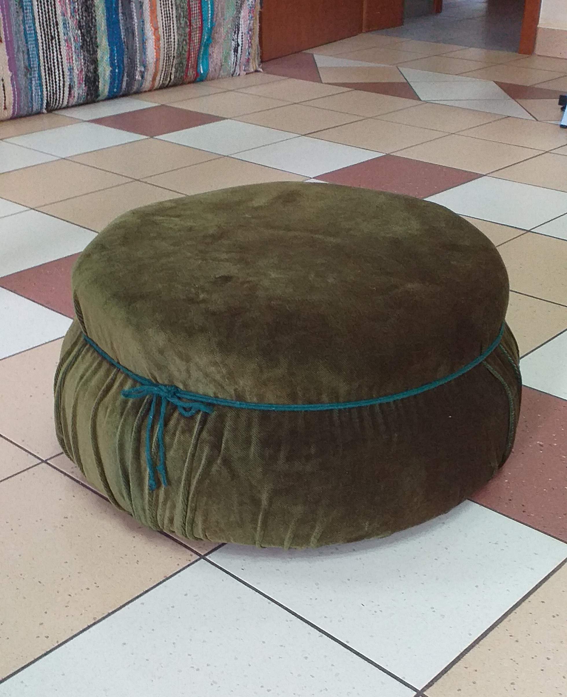 pufa z opony tapicerowana zielonym pluszem.