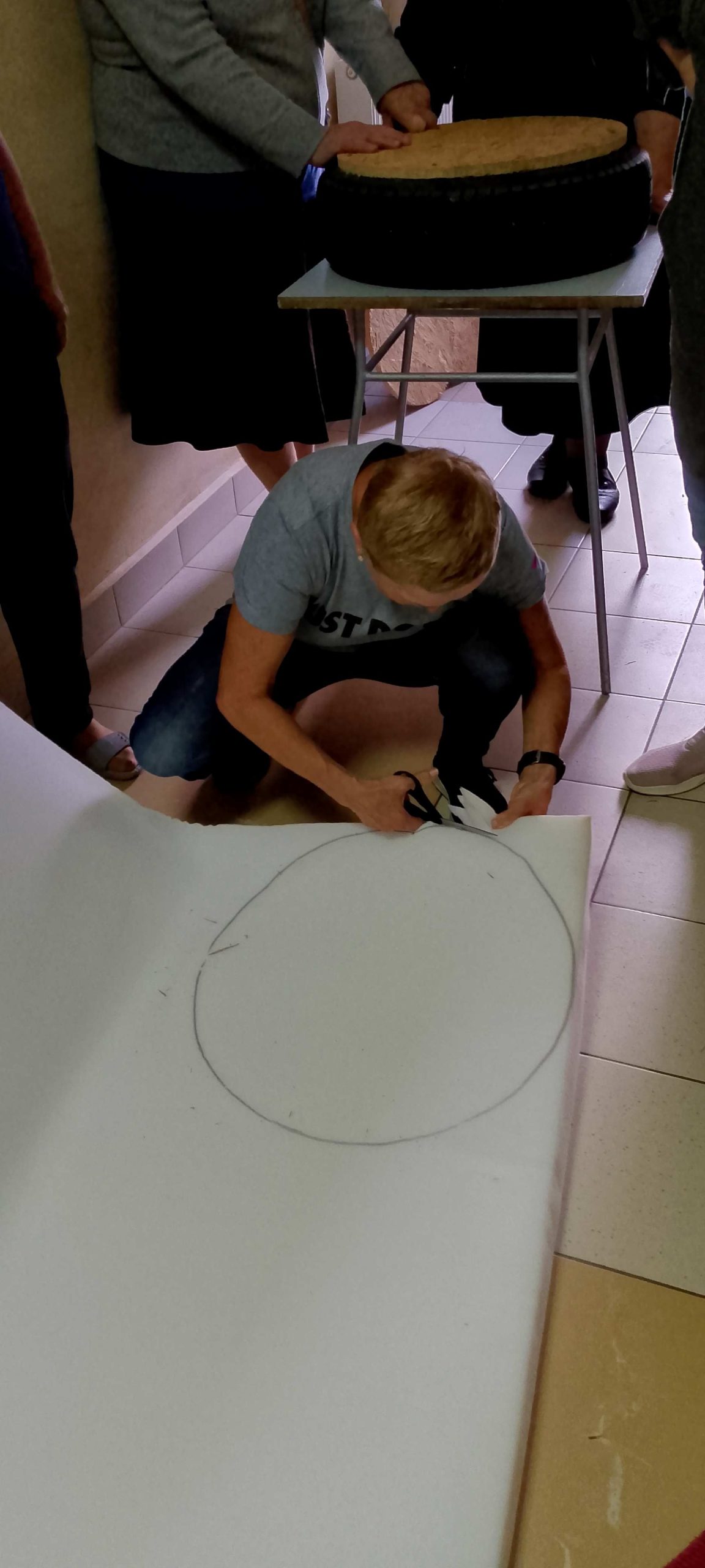Uczestniczka warsztatów wycina koło z pianki tapicerskiej.