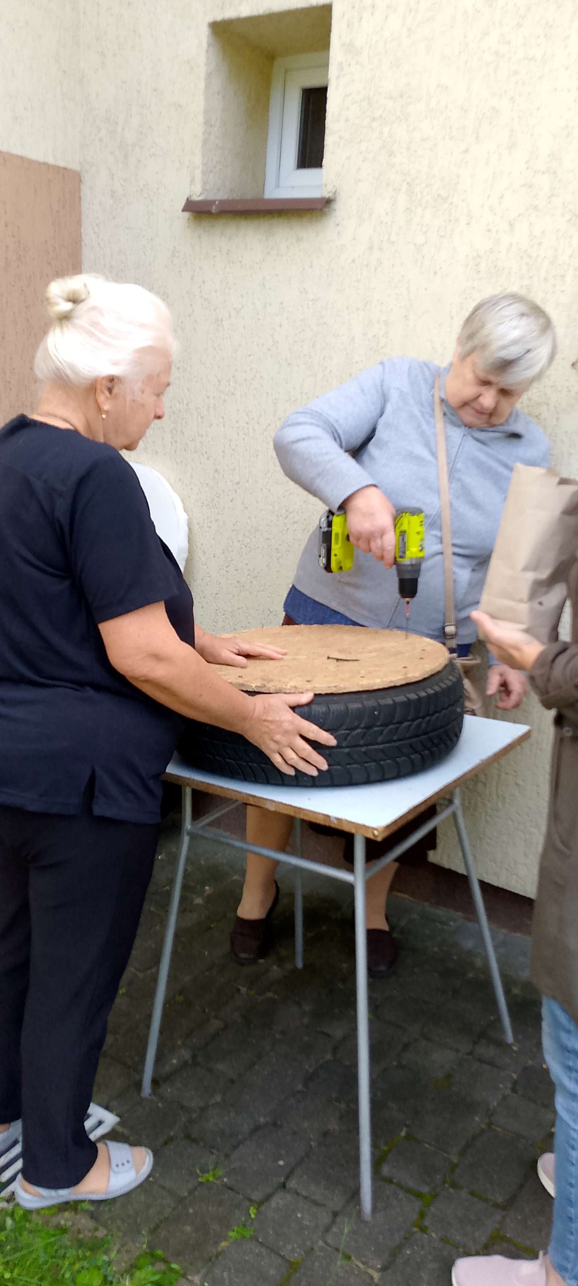 Uczestniczka przykręca wycięte ze sklejki koło do opony.