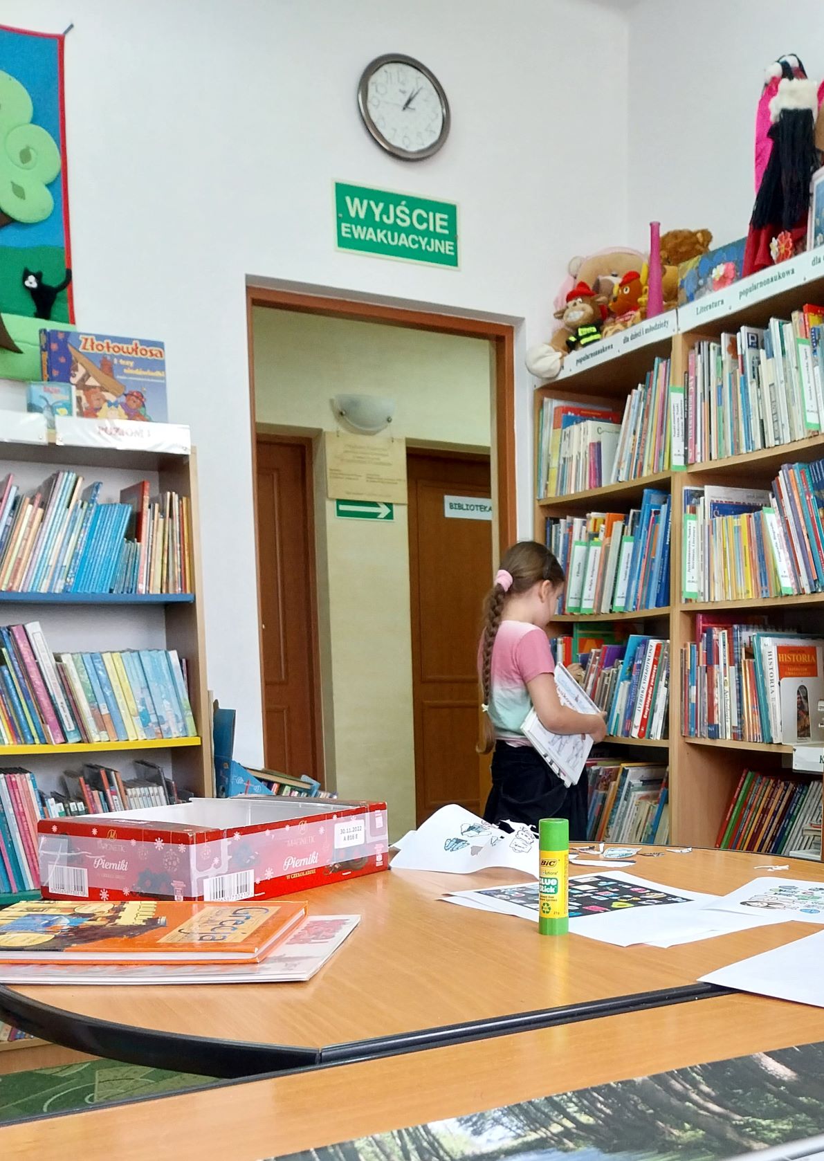 dziewczynka przeszukuje półki biblioteczne pełne książek, które potem czyta w kąciku czytelniczym