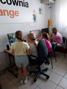 grupa dziewcząt siedzi przed komputerami