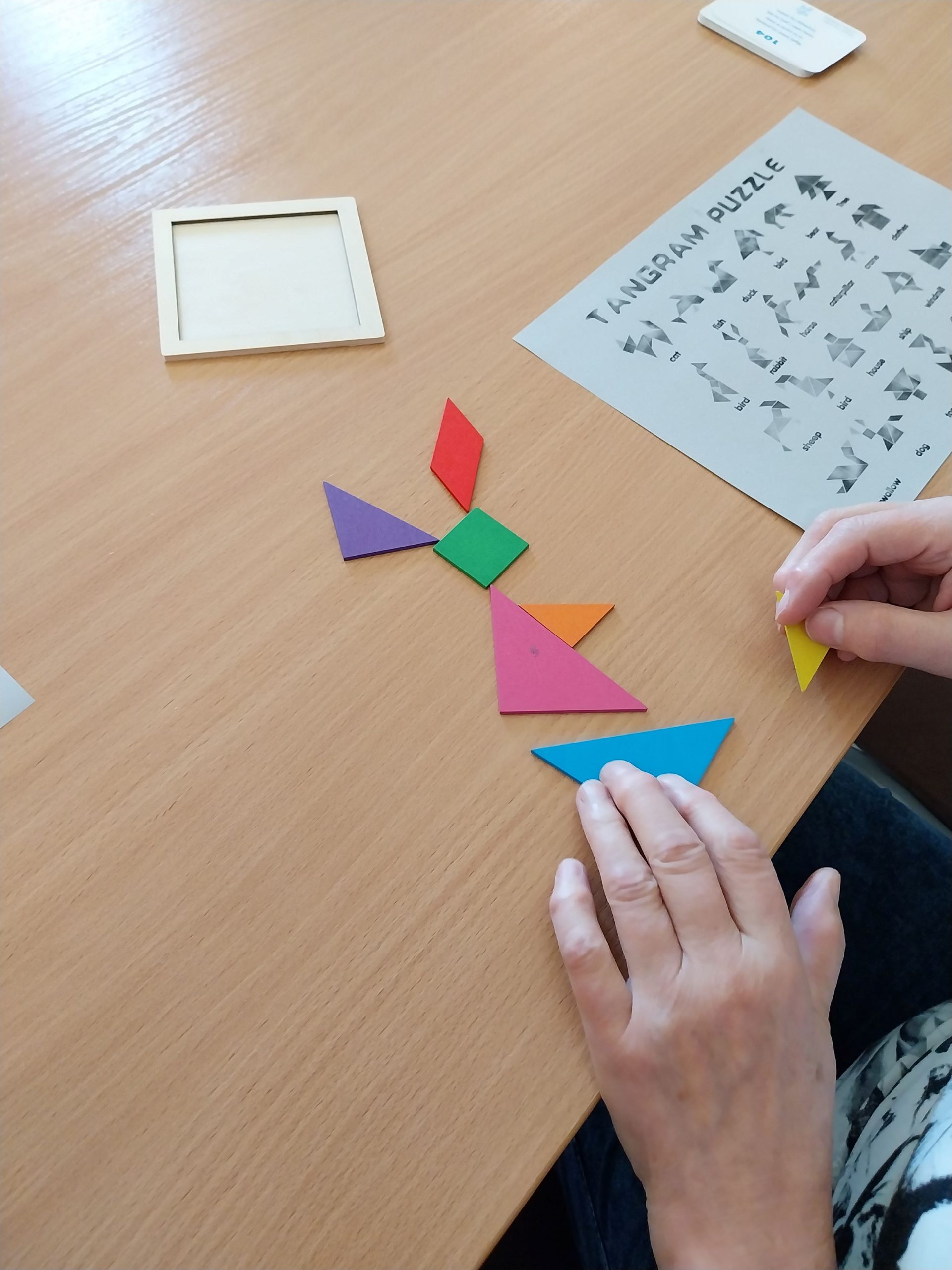 na stoliku uczestniczka zajęć układa tangram - kolorowe elementy, które przybierają kształt zająca