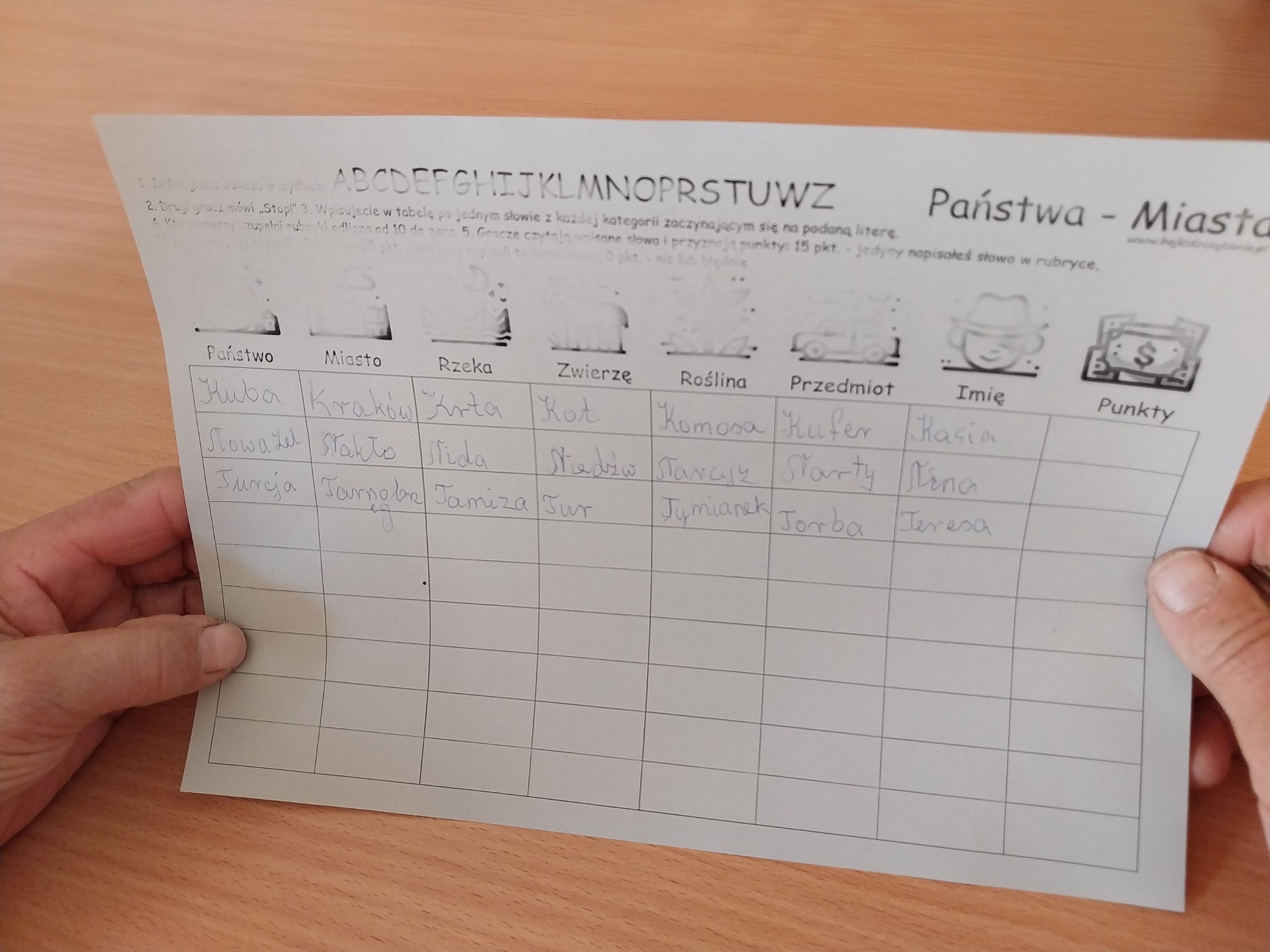uczestniczka trzyma w ręku kartę zadaniową z serii miasta, państwa