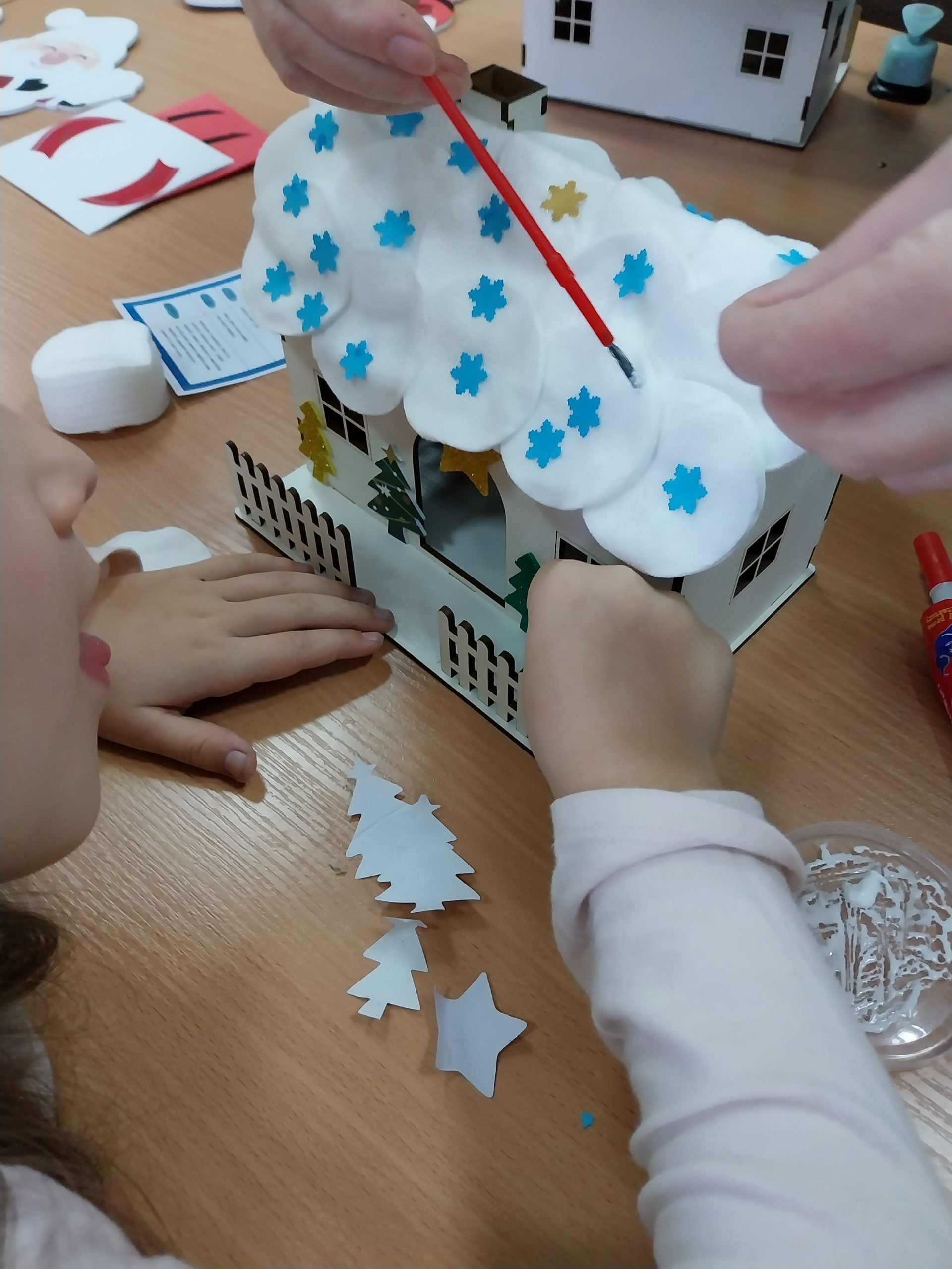 Uczestniczka z mamą ustawiają płotek oraz pokrywają dach niebieskimi gwiazdkami