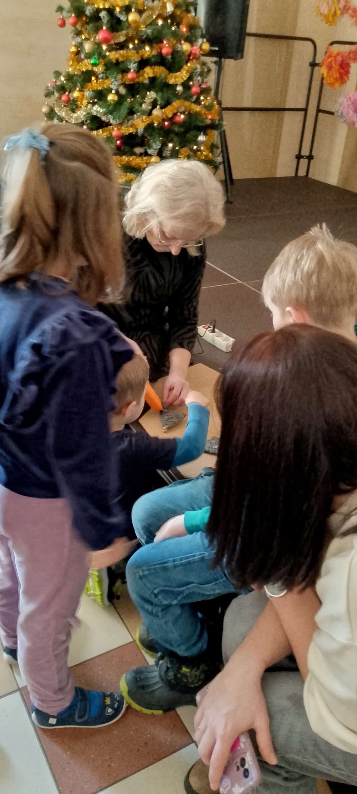 Dzieci obserwują przyklejanie oczek zwierzątkom z kartoników.