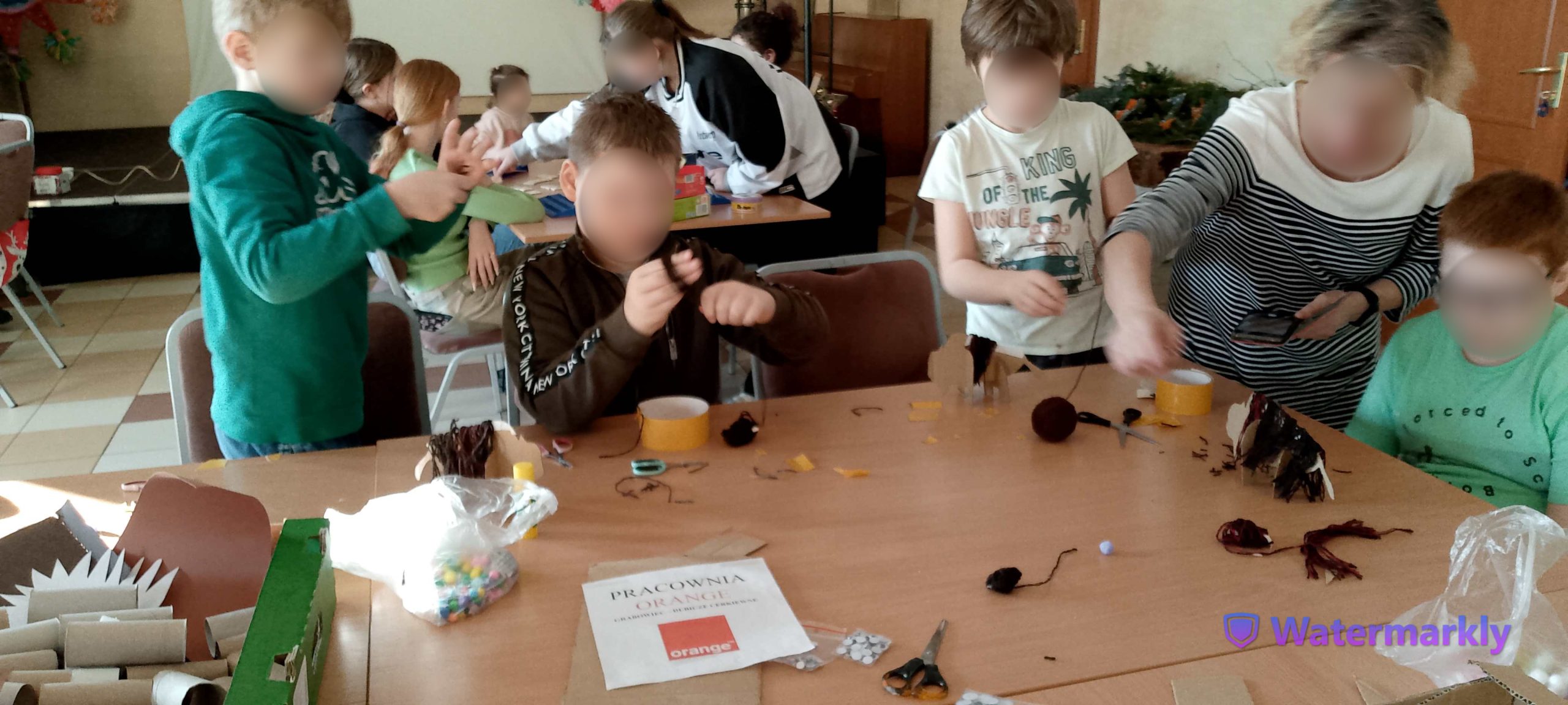 Dzieci oklejają brązową włóczką szablon żubra.