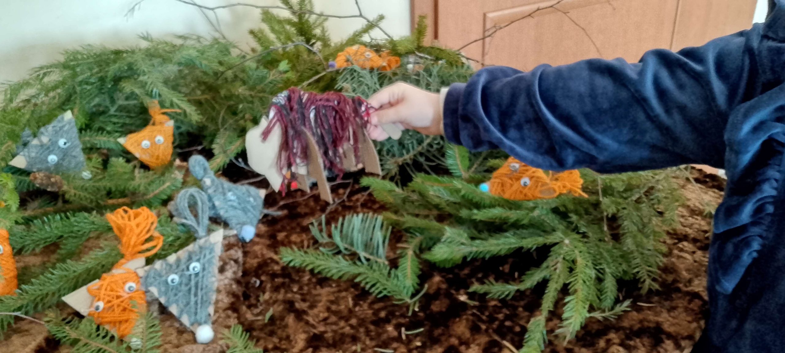 Dziewczynka stawia wykonanego z brązowej włóczki żubra