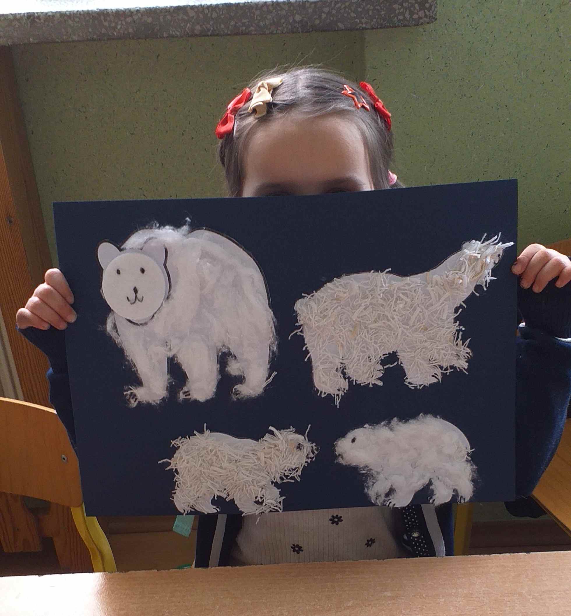 Dziewczynka prezentuje swoja pracę, na której jest niedźwiedź, niedźwiedzica i dwa niedźwiadki.