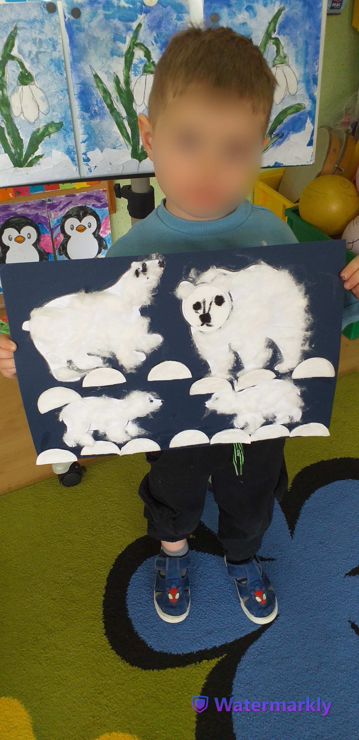 Chłopczyk prezentuje swoją pracę, na której są: niedźwiedzica, niedźwiedź i dwa niedźwiadki.