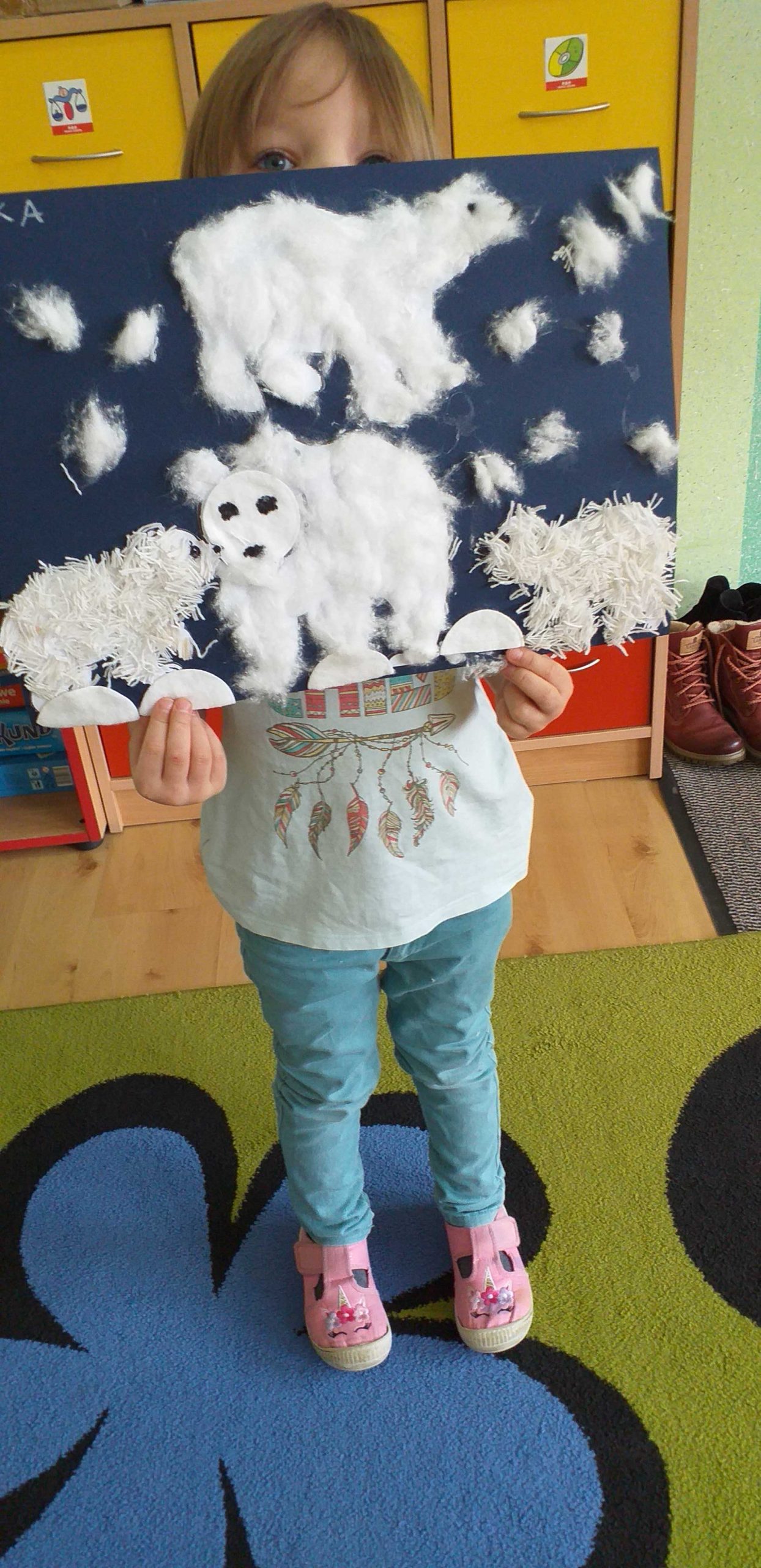 Dziewczynka prezentuje swoją pracę, na ktorej jest niedźwiedzia rodzina.