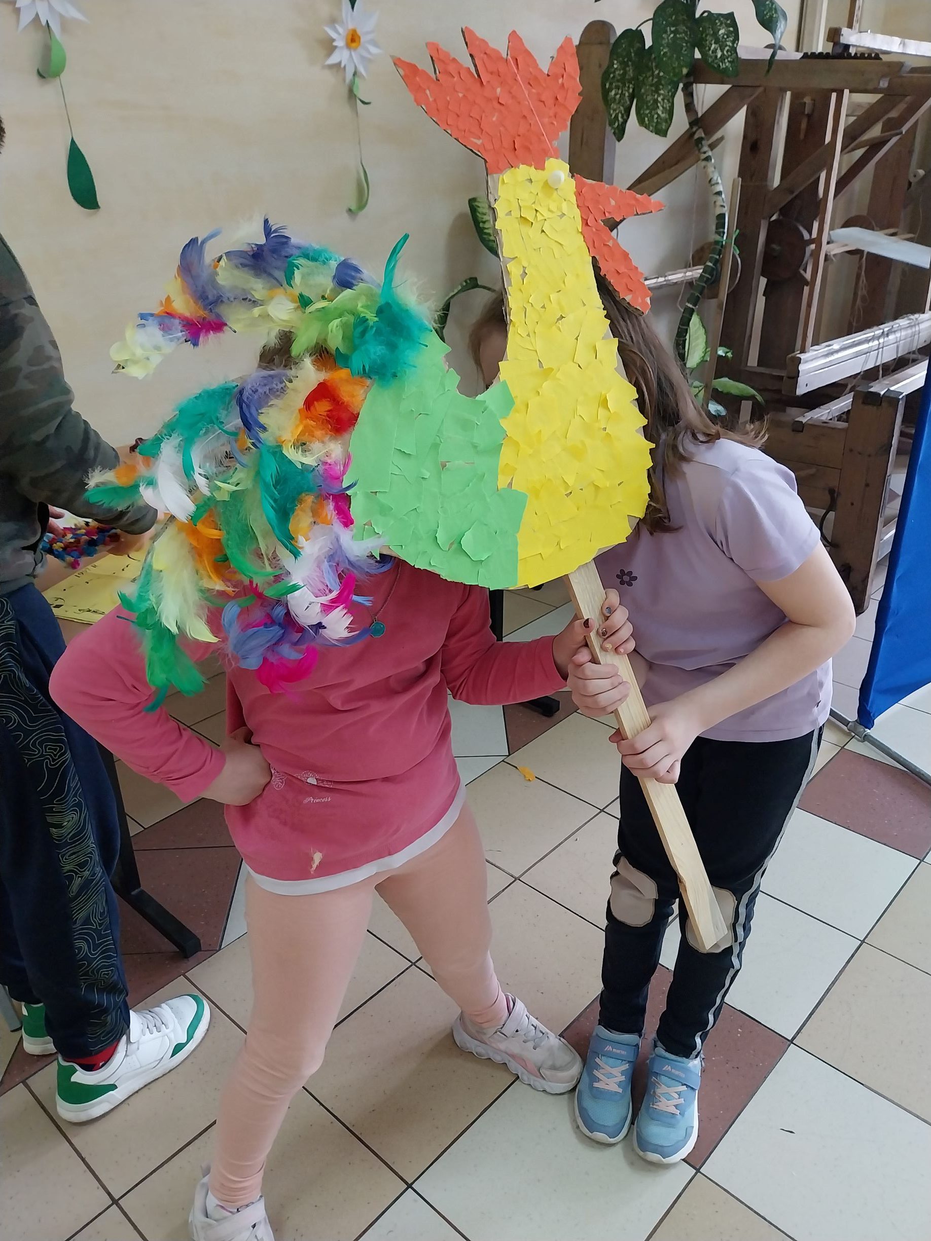 Dziewczynki trzymają własnoręcznie wykonanego kolorowego koguta.