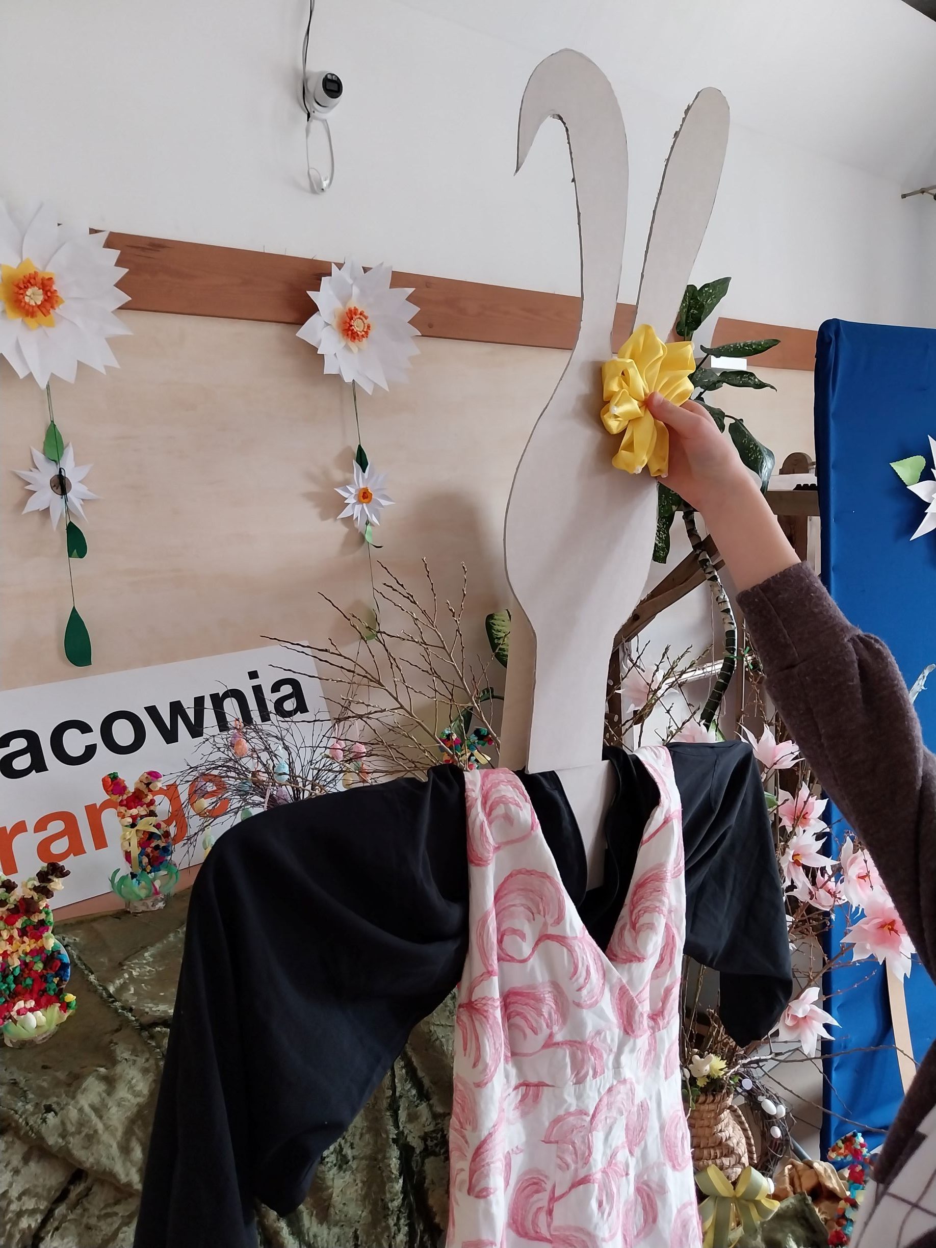 Dziewczynka przykleja ozdobę z żółtej wstążki na ucho 