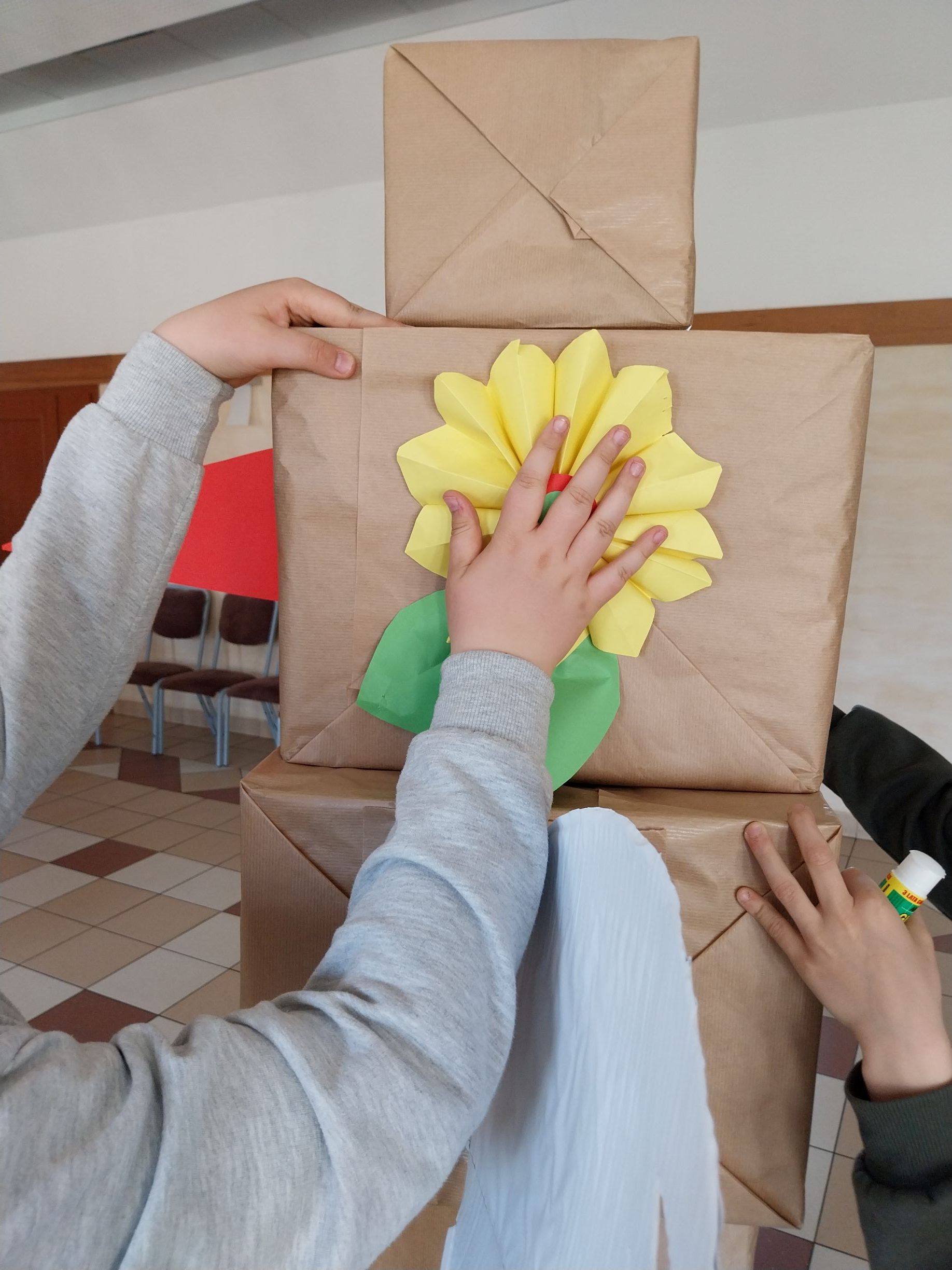 chłopcy przyklejają klejem na gorąco pierwsze słoneczne kwiaty