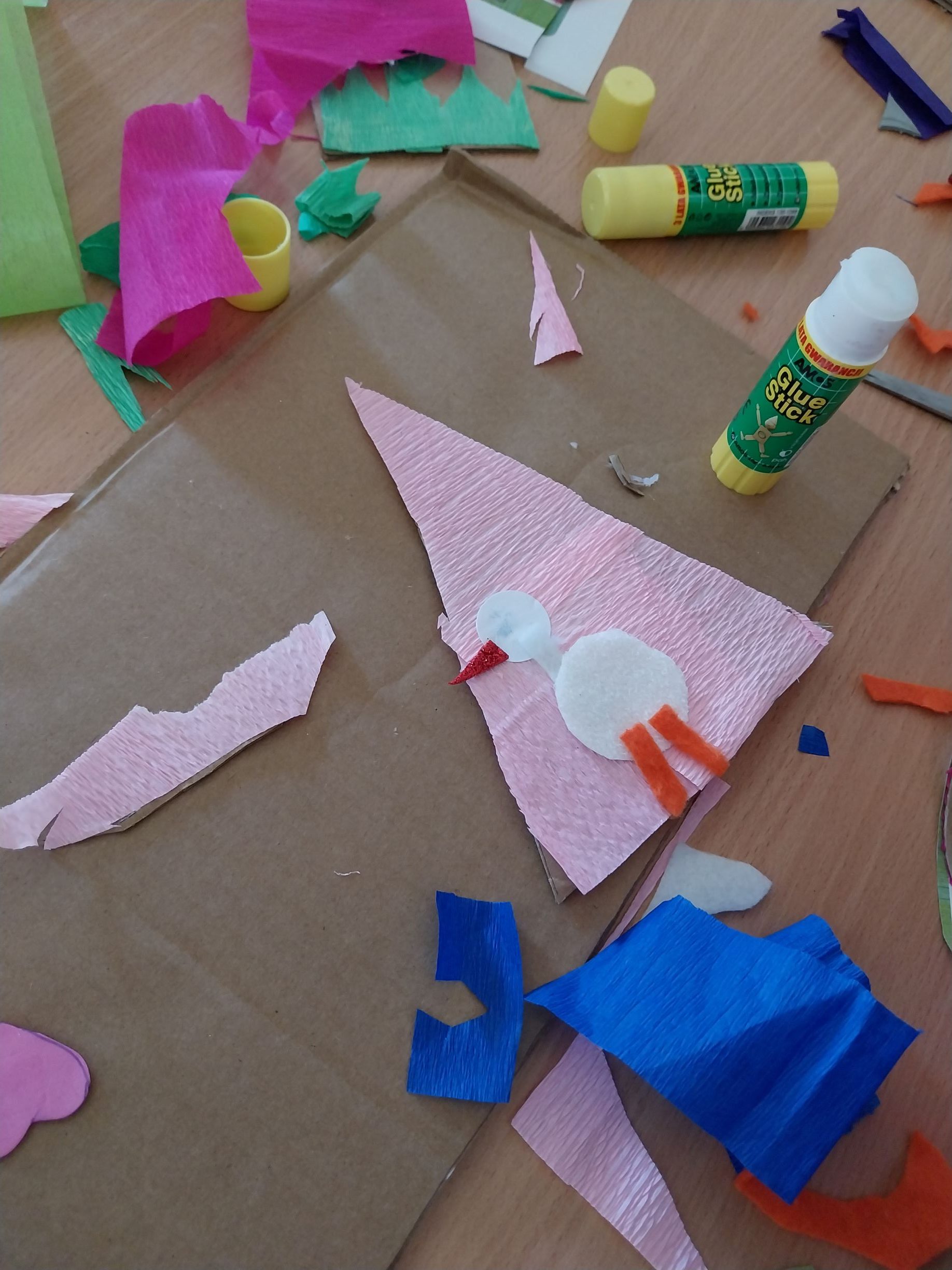 prezentacja małego bociana na trójkątnym podkładzie kartonowym