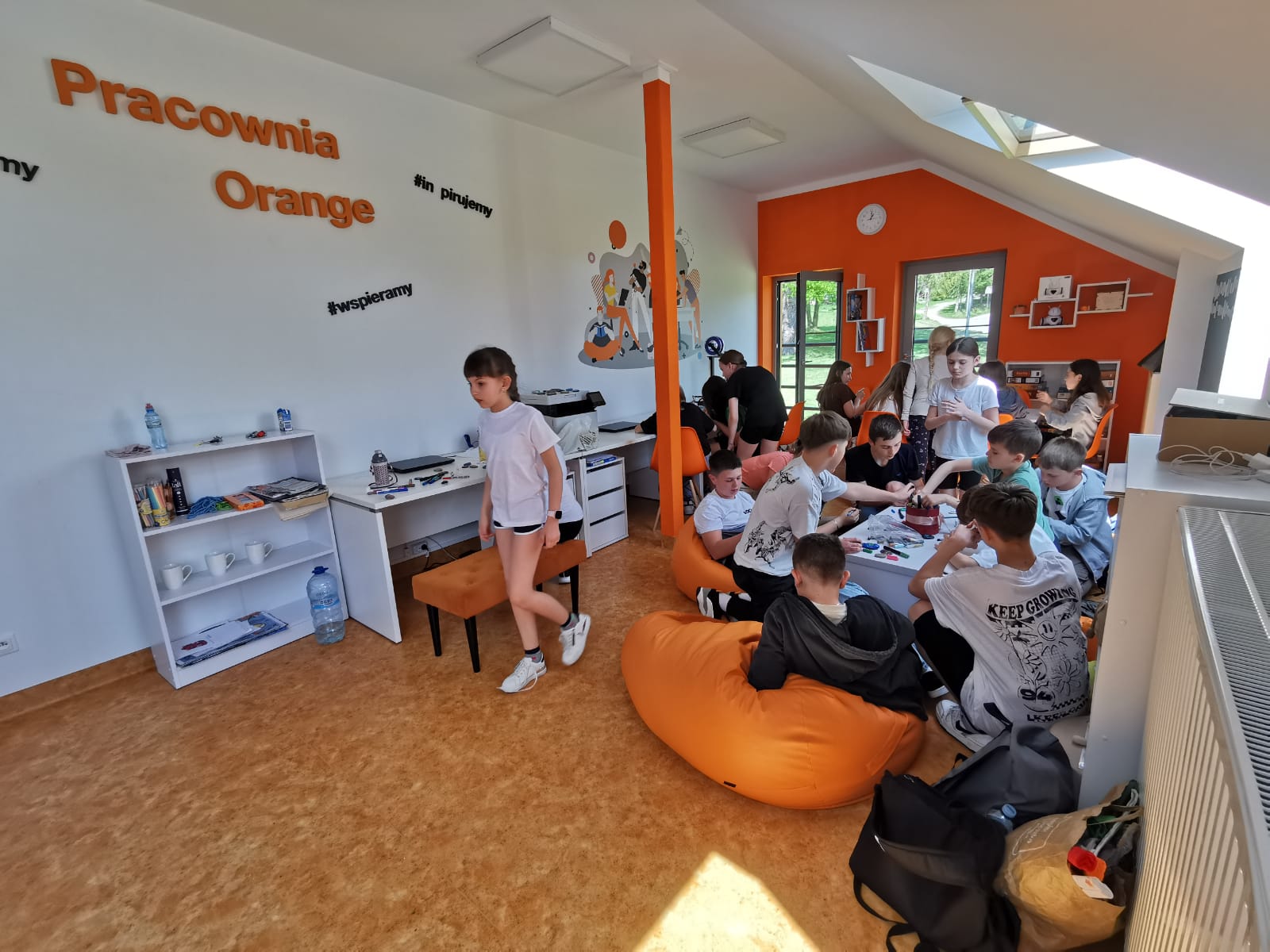 Kolorowe zdjęcie. Grupa młodzieży maluje kamienie w Pracowni Orange.
